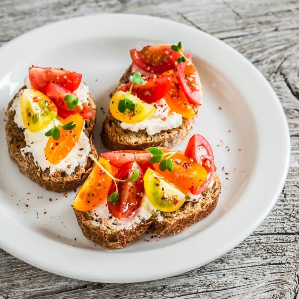 Drei Bruschetta auf einem Teller. Tomaten, Käse und Kräuter auf Brot.