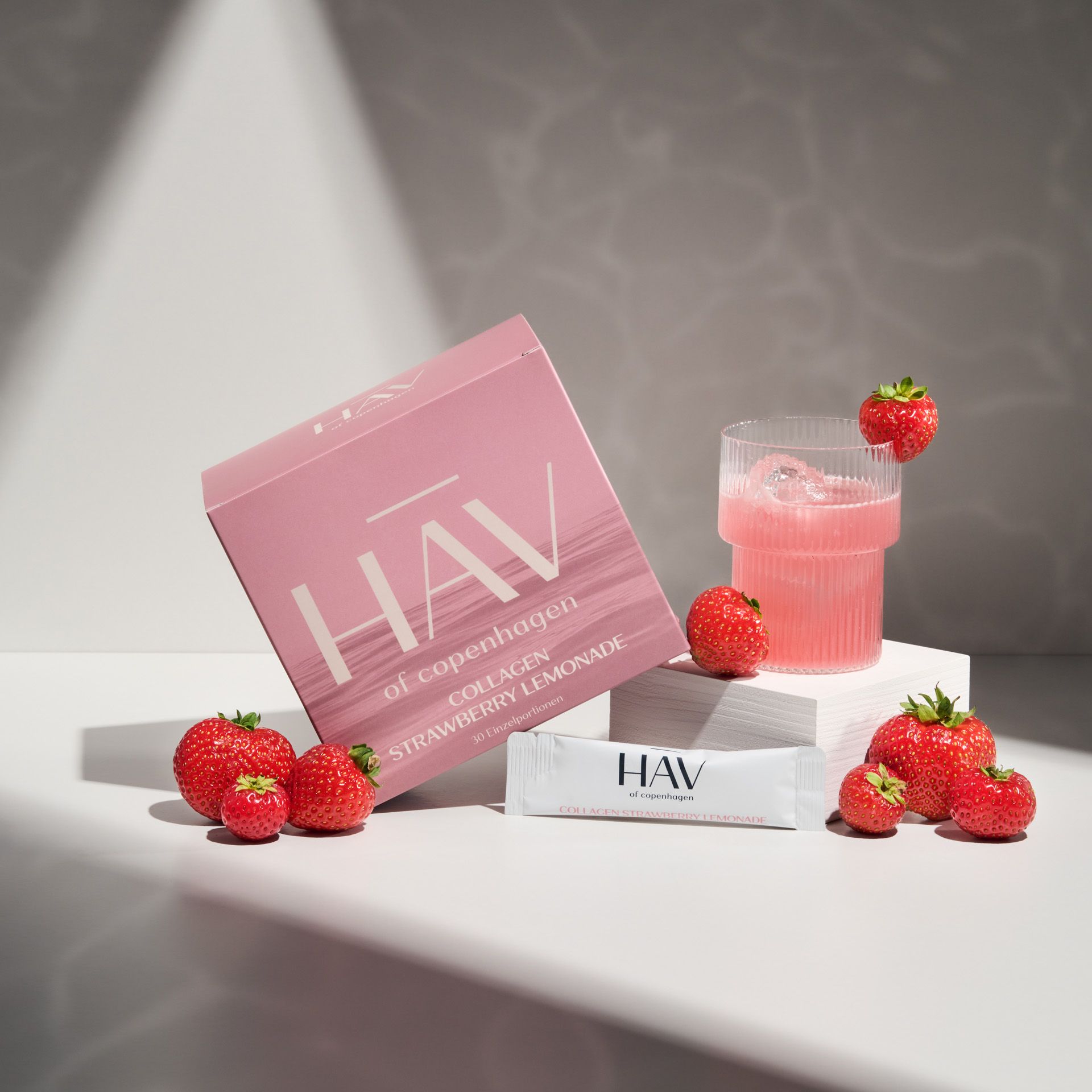 Produktverpackung, Trinkglas, Erdbeeren und ein Beutel. HAV Collagen Strawberry Lemonade. Weißer Beutel.
