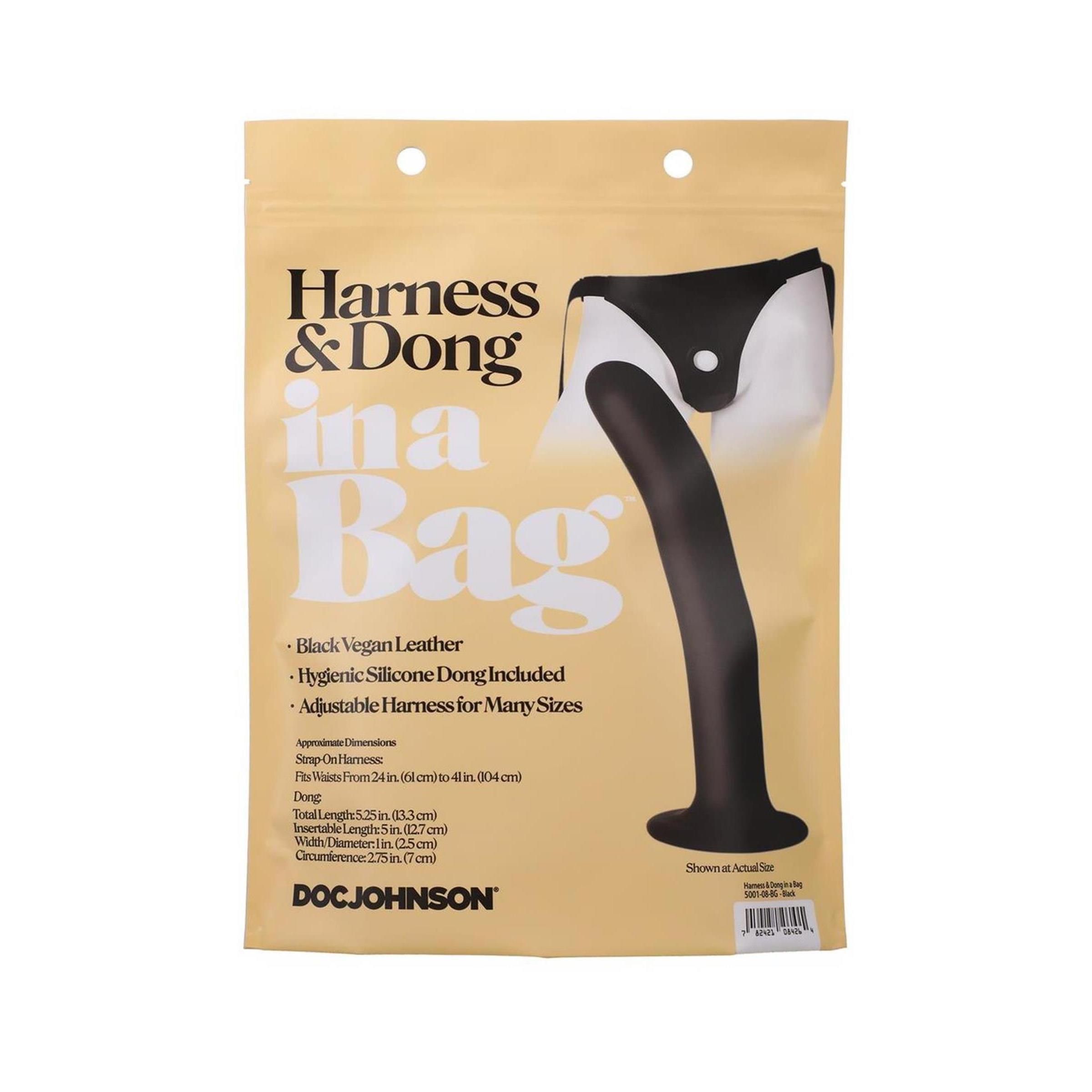 Beige Verpackung mit Produktabbildung. Enthält schwarzen Dong und Harness. Text: "Black Vegan Leather", "Hygienic Silicone Dong".