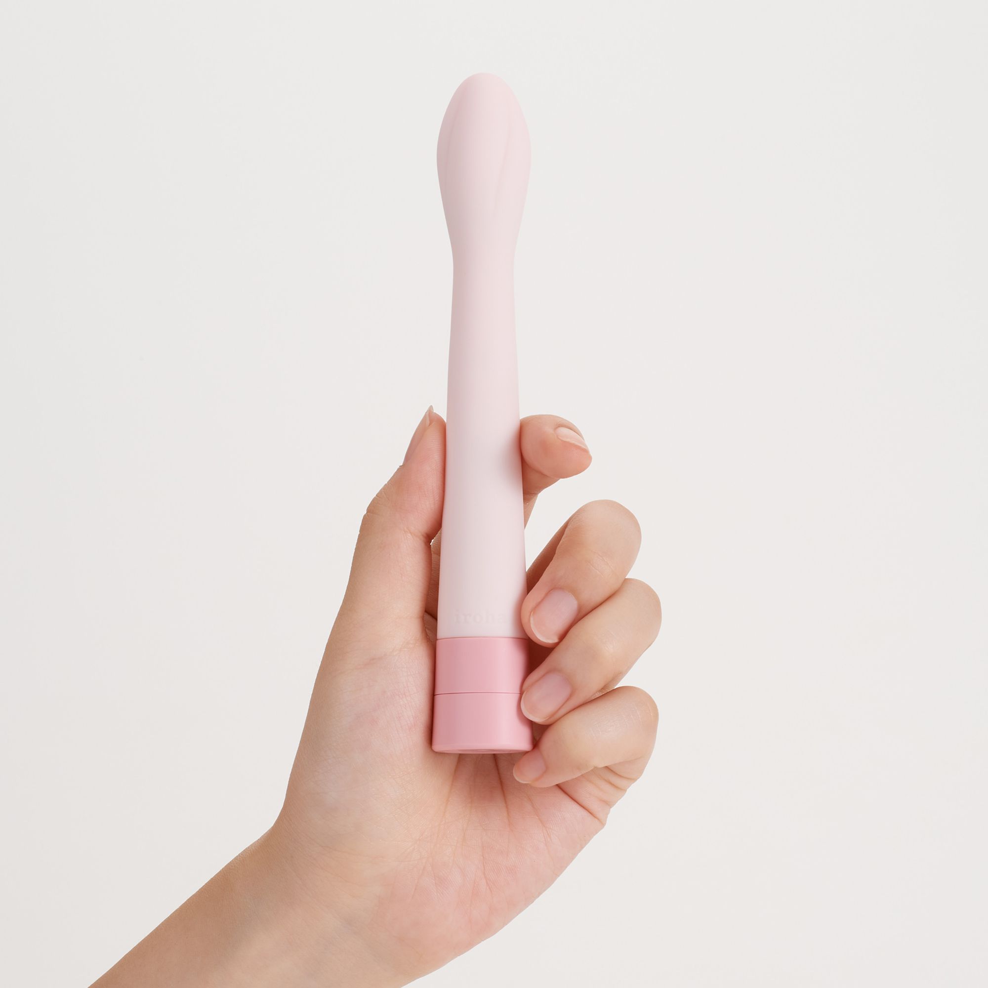 Rosa Vibrator in einer Hand gehalten. Zylindrische Form, rosa Basis.