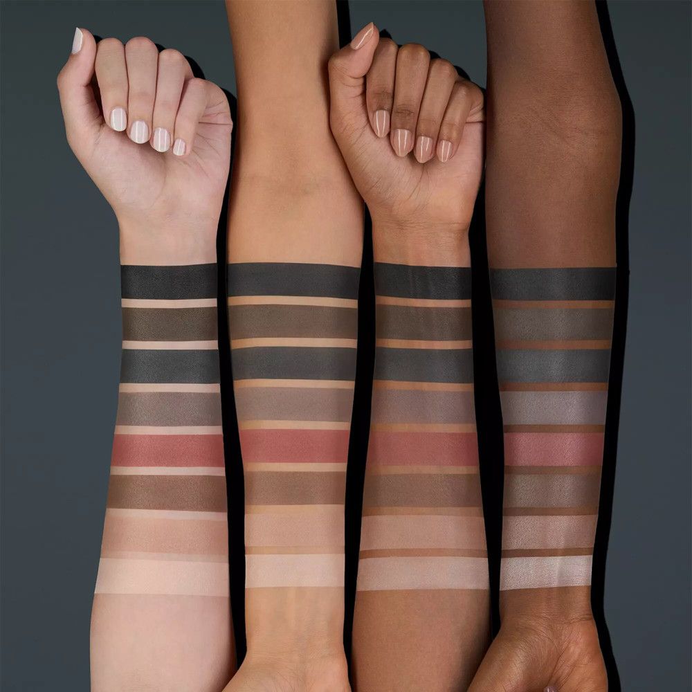 Arme mit verschiedenen Hauttönen zeigen Lidschatten-Swatches. Verschiedene Brauntöne, Rosa und Grau.