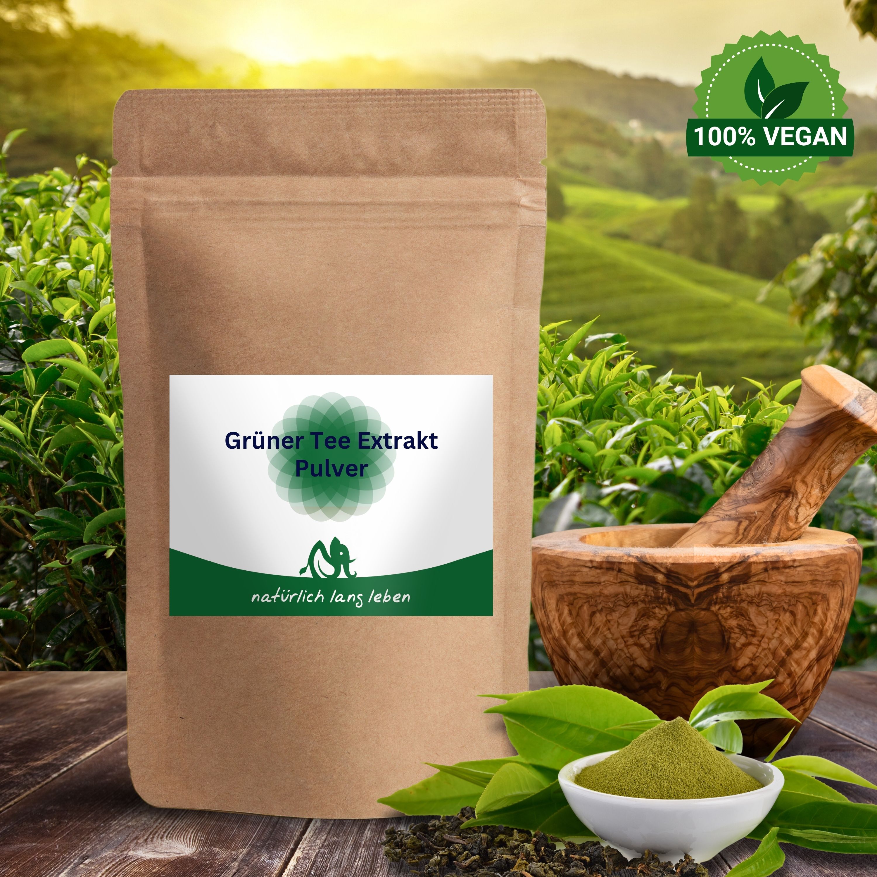 Braune Tüte mit grünem Etikett. Grüner Tee Extrakt Pulver. Logo: Elefant. Text: natürlich lang leben. Im Hintergrund: Landschaft, Mörser.