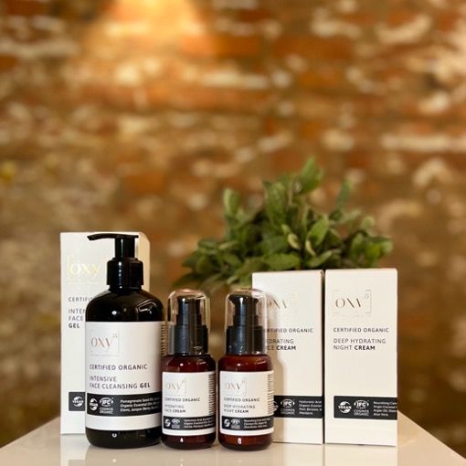 Drei Kosmetikprodukte mit Verpackung. Flaschen und Kartons. Text: OXY8, Certified Organic.