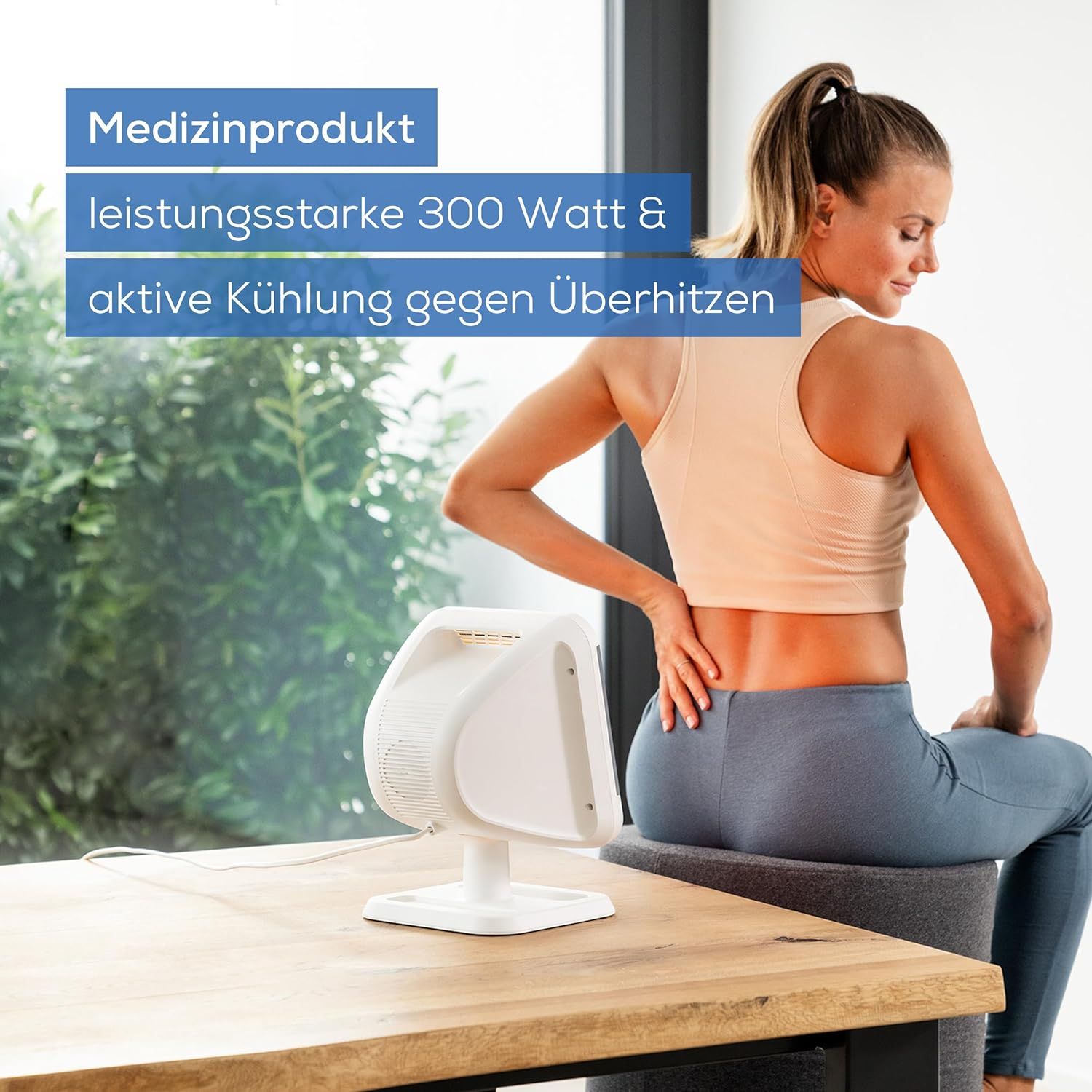 Weißer Infrarot-Wärmestrahler. Frau sitzt vor dem Gerät. Aufschrift: Medizinprodukt, leistungsstarke 300 Watt & aktive Kühlung gegen Überhitzen.