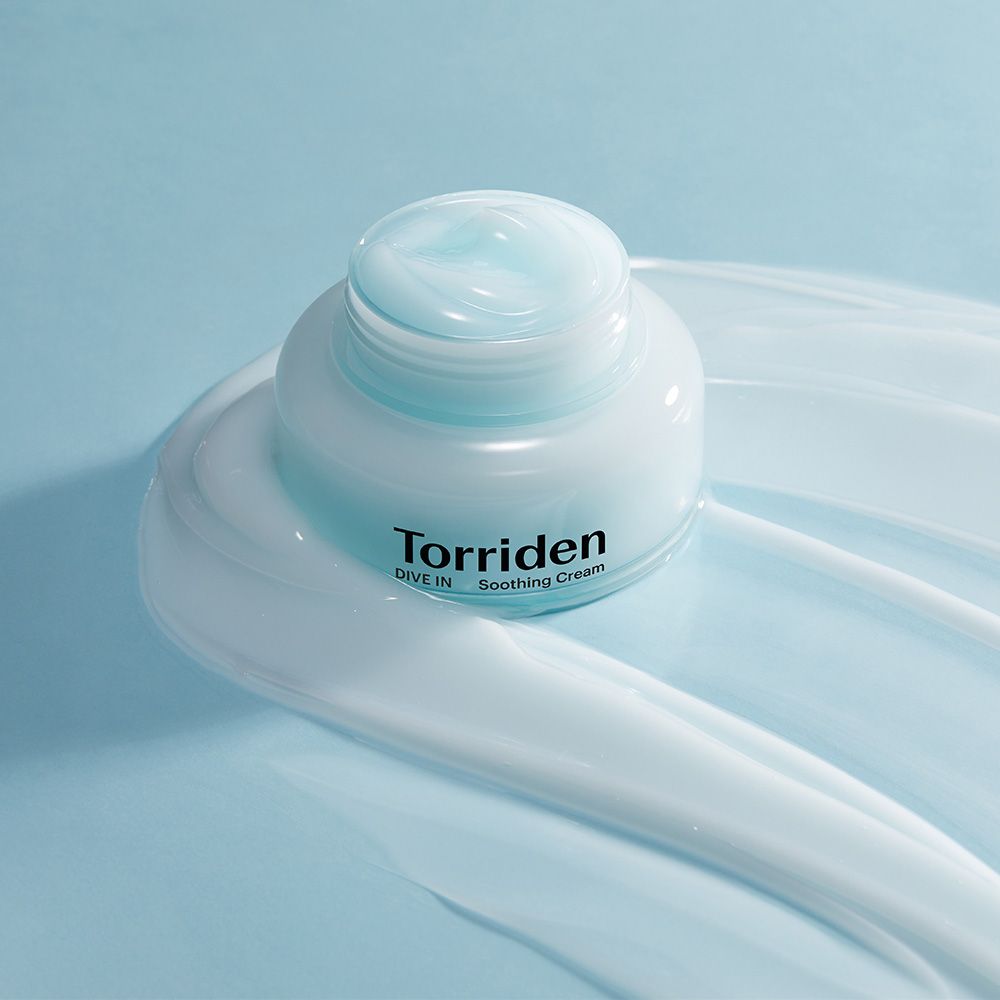 Torriden DIVE IN Soothing Cream in einem Tiegel, umgeben von cremigen Streifen.