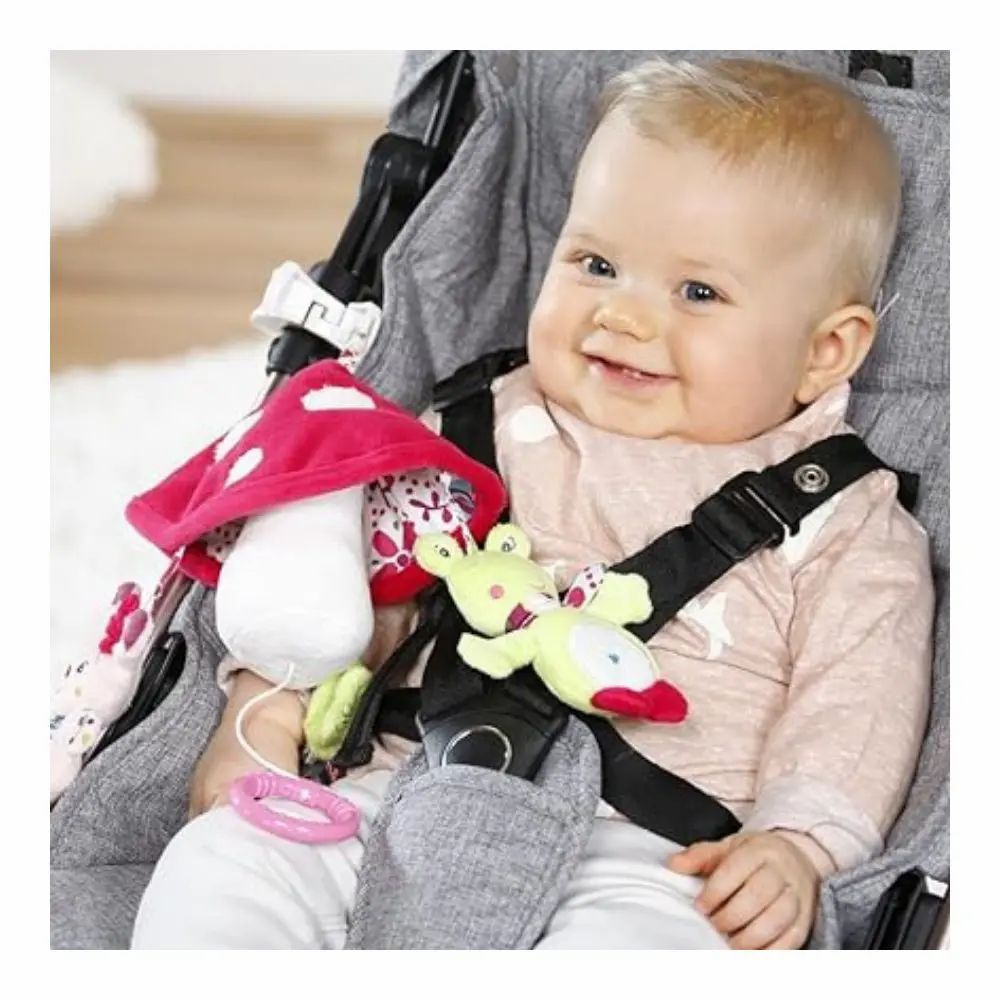 Baby im Kinderwagen mit Mobile. Mobile mit Pilz, Reh und Frosch. Baby sitzt im Kinderwagen und lächelt.