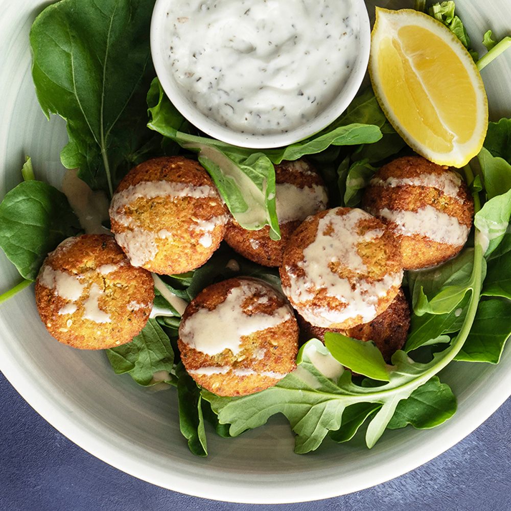 Falafel mit Sauce und Salat in einer Schüssel. Draufsicht.
