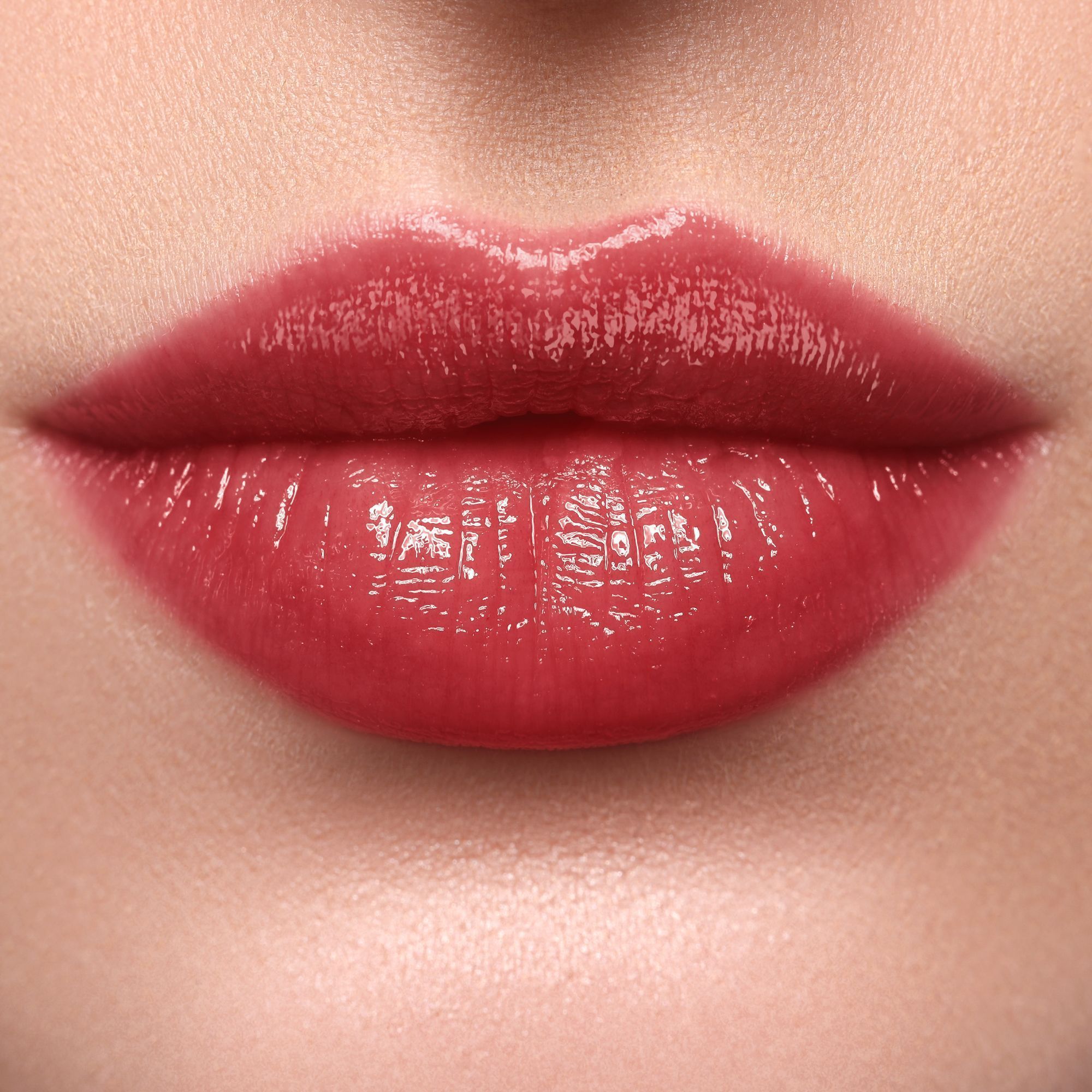 Nahaufnahme von Lippen, die mit WYCON Cosmetics Hydrasheer Glossy Lipstick in Cherrywood geschminkt sind. Die Lippen sind glänzend und haben einen tiefroten Farbton. Die Haut um die Lippen ist glatt und ebenmäßig.