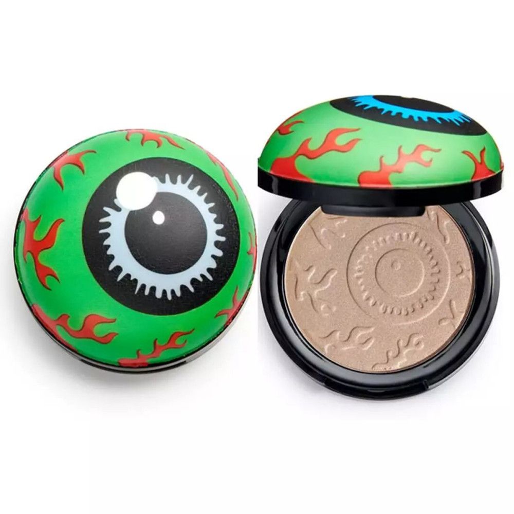 Highlighter in Augapfel-Form. Grünes Gehäuse mit Augenmotiv. Gehäuse geöffnet, Puder sichtbar. Schwarzer Rand.