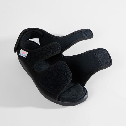 Schwarze Sandale mit Klettverschluss und offenem Zehenbereich. Ein Riemen über dem Spann, einer über den Zehen.