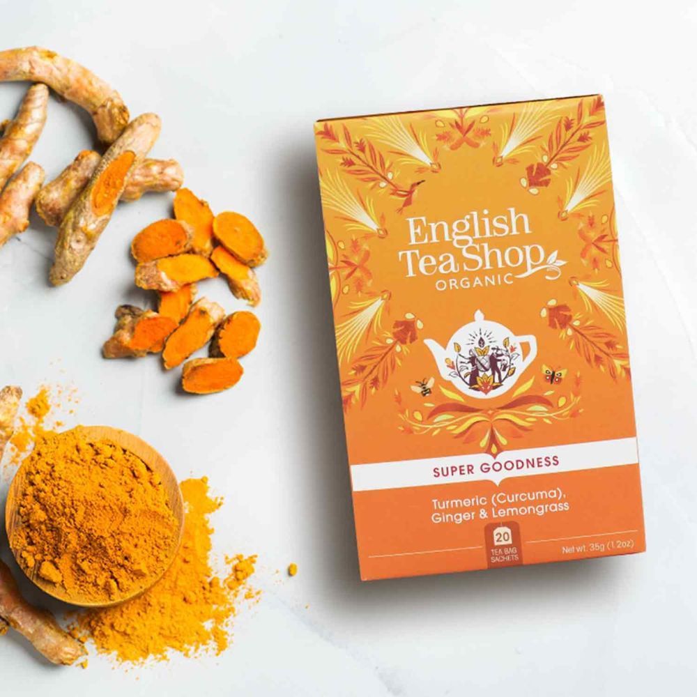 Theebox mit Kurkuma, Ingwer und Zitronengras. Daneben Kurkuma-Pulver in Schale und Kurkuma-Stücke. English Tea Shop Organic.