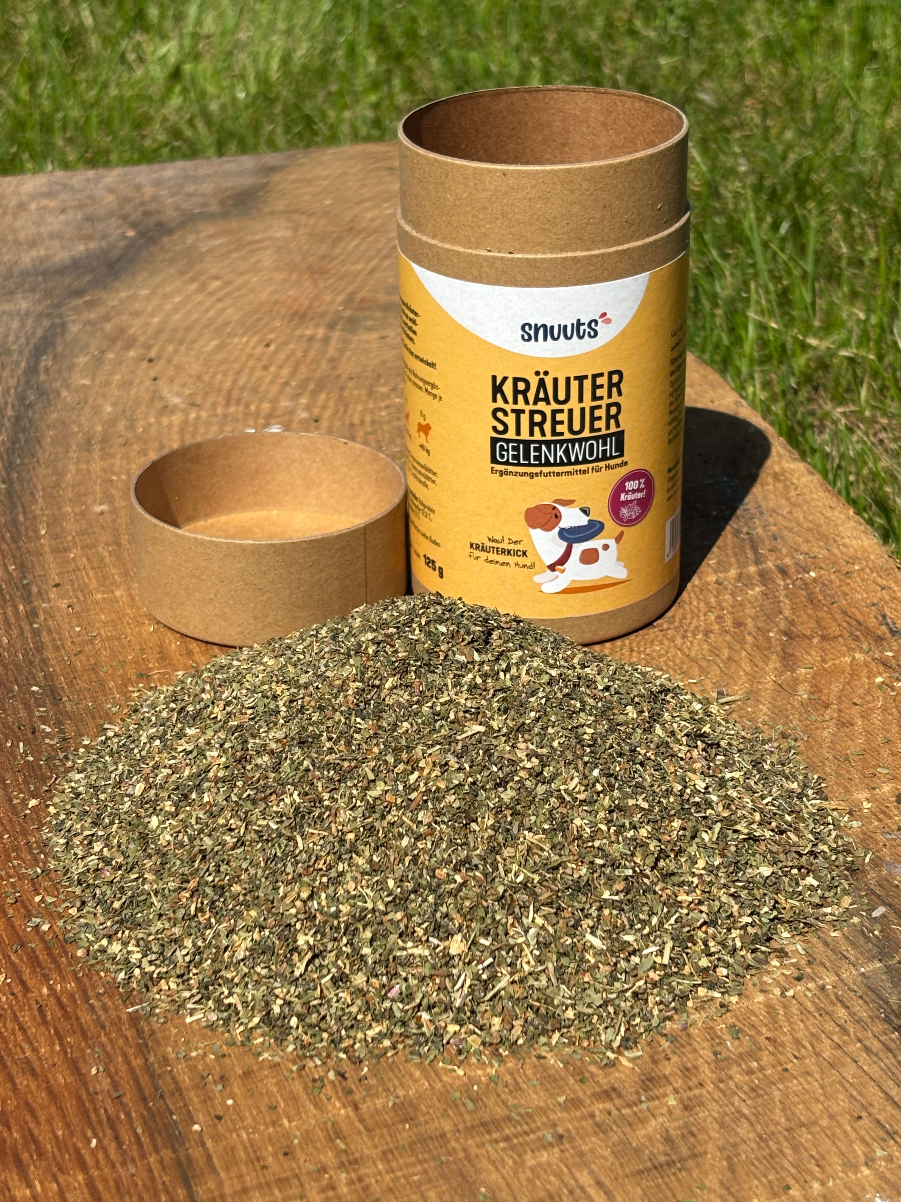 Zylindrische Dose und Kräuter auf Holz. Dose: snuuts Kräuterstreuer Gelenkwohl. Kräuterhaufen daneben. Deckel daneben.
