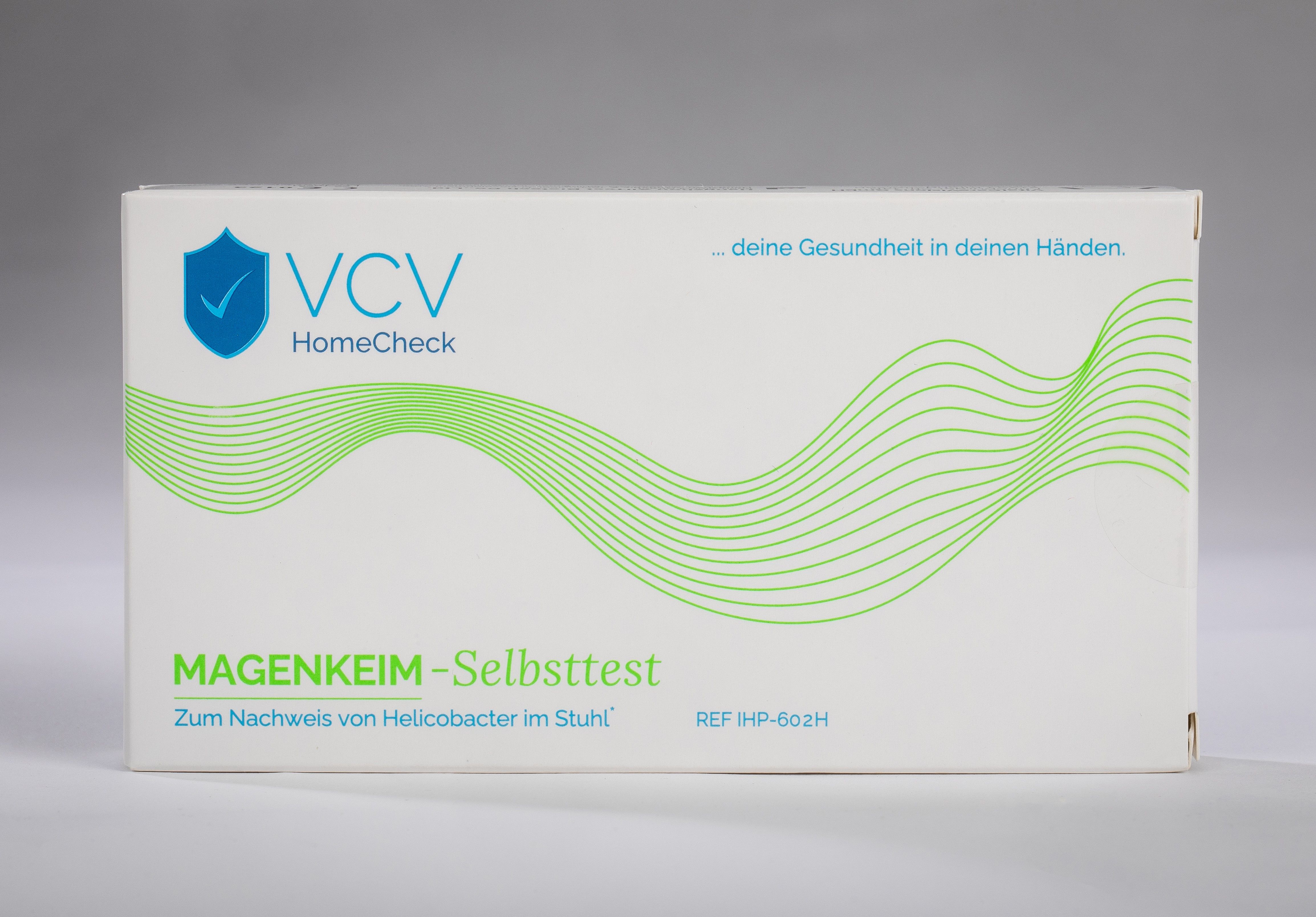 VCV HomeCheck Magenkeim Schnelltest-Verpackung. Weiß, mit grünem Wellenmuster und Logo. Text: Magenkeim-Selbsttest.