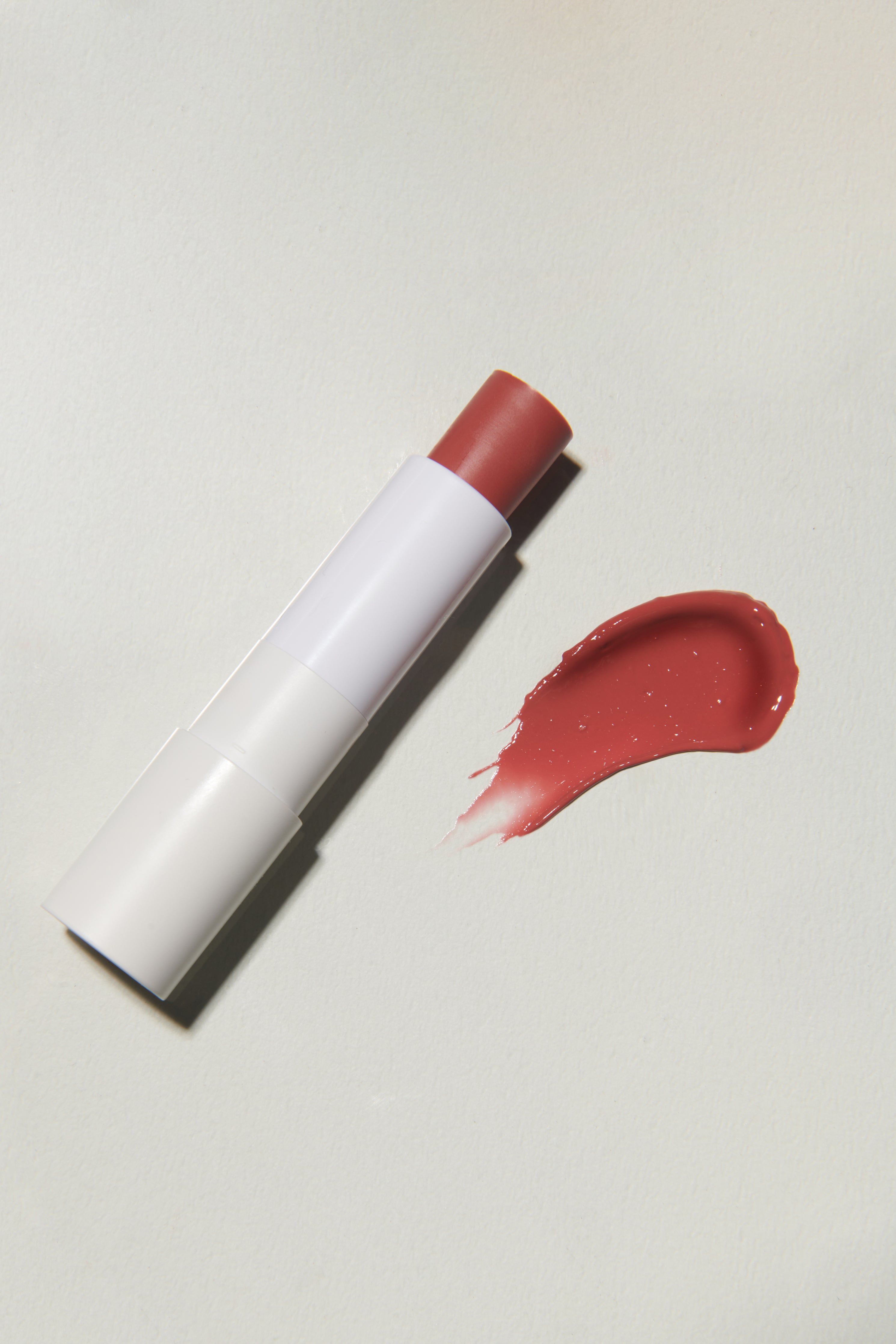 Weißer Lippenbalsam und eine Spur des Balsams. Der Balsam ist rot.