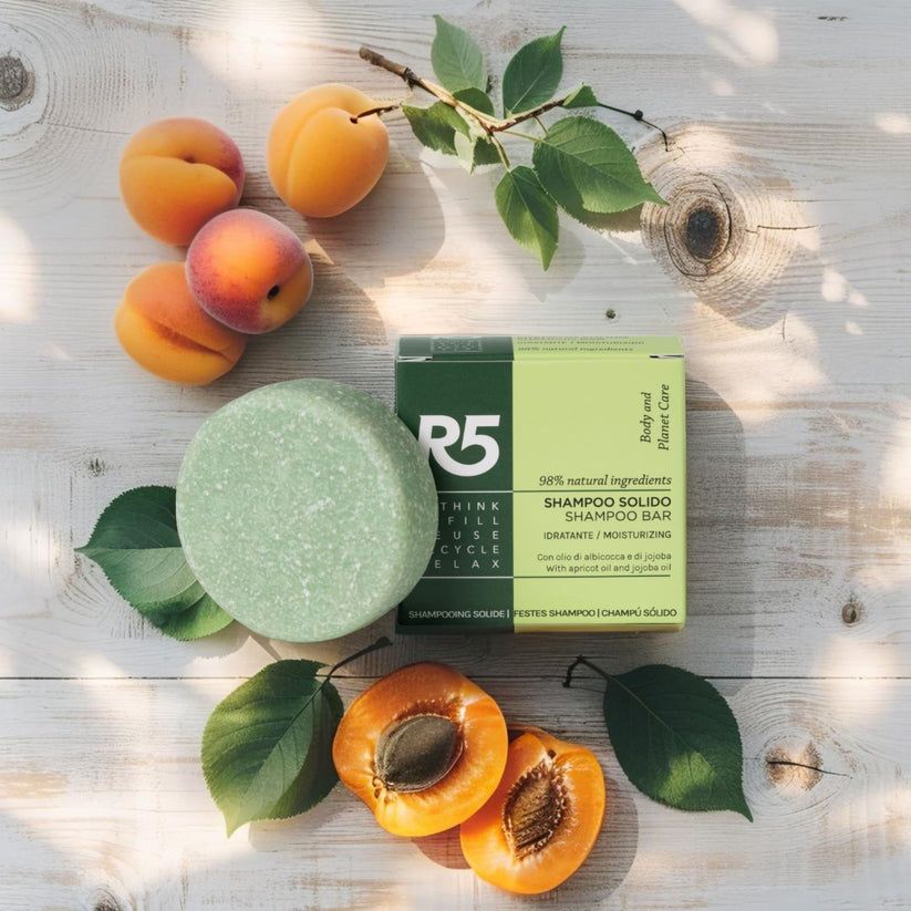 Grünes, rundes Shampoo-Stück und Schachtel mit Text. Aprikosen und Blätter liegen auf Holz. Vegan.