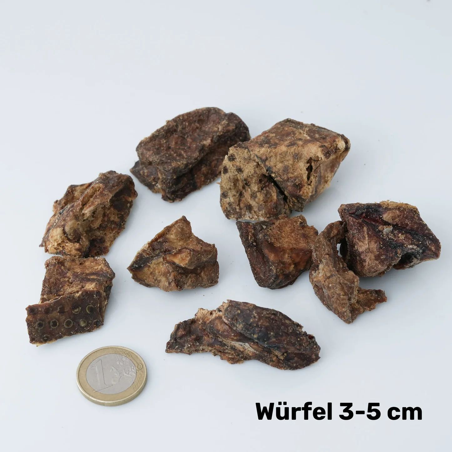 Hundefutter-Snack aus Rinderlunge. Braune, würfelförmige Stücke. Münze daneben. Text: Würfel 3-5 cm.