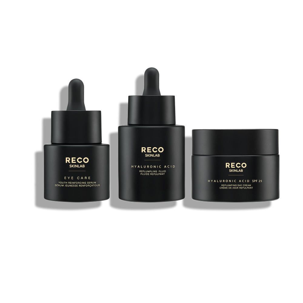 Drei schwarze Kosmetikprodukte. Links: Serum für Augen. Mitte: Hyaluronsäure-Fluid. Rechts: Tagescreme mit SPF 20. Alle mit Logo.