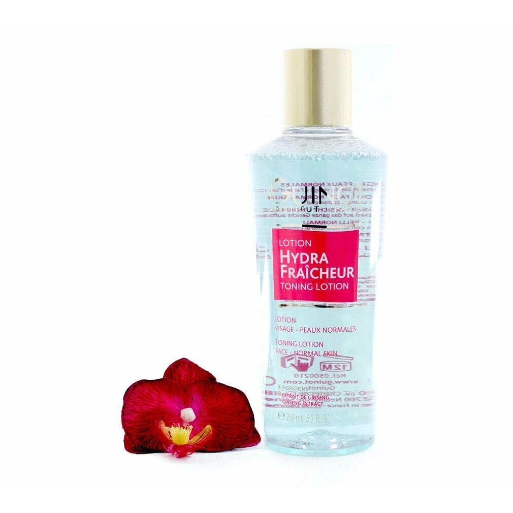 Guinot Lotion Hydra Fraicheur. Flasche mit goldfarbenem Deckel. Rotes Etikett. Rote Orchidee daneben. Klare Flüssigkeit sichtbar.