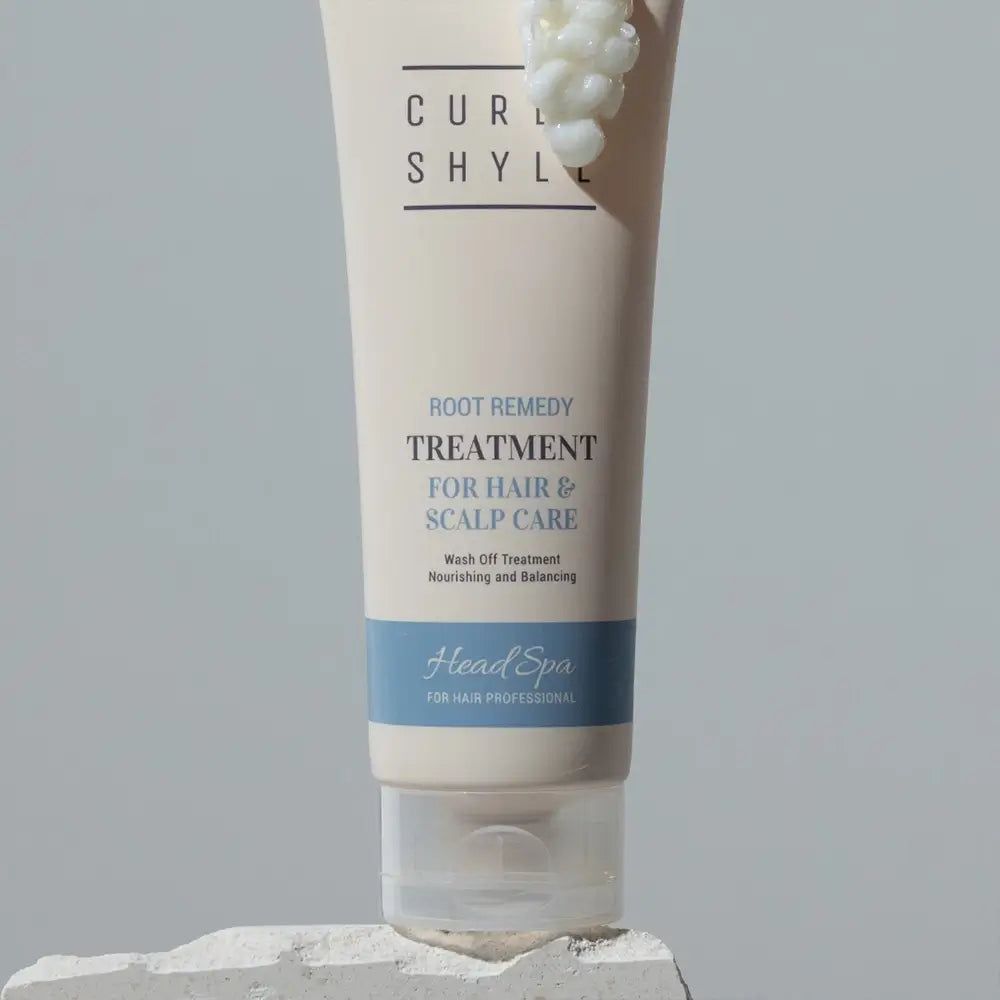 Beige Tube mit Produkttext. Aufschrift: CURLY SHYLL, Root Remedy Treatment, für Haar & Kopfhautpflege. Blaue Leiste: Head Spa.