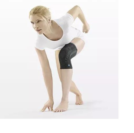 Person mit schwarzer Kniebandage beim Sport. Trägt weißes Oberteil. Kniebandage am Bein.