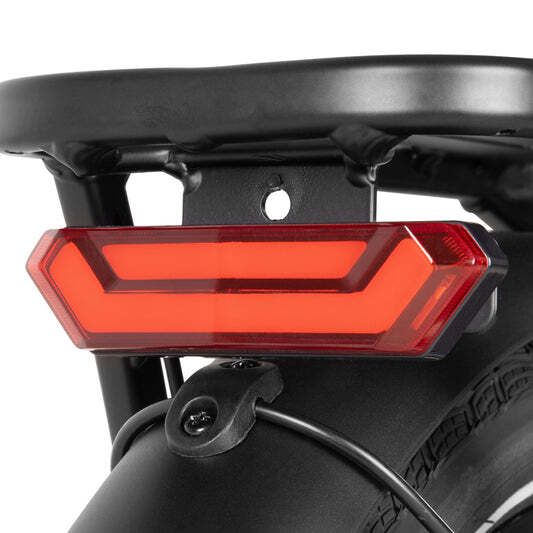 Rücklicht an einem schwarzen Fahrrad. Rotes, rechteckiges Licht. Montiert an einem Gepäckträger.