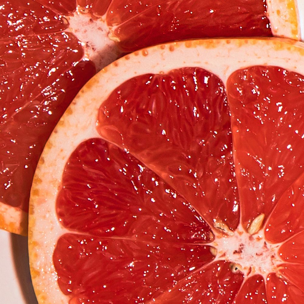 Nahaufnahme von zwei Grapefruit-Hälften. Rotes Fruchtfleisch mit hellrosa Schale. Sichtbare Kerne.