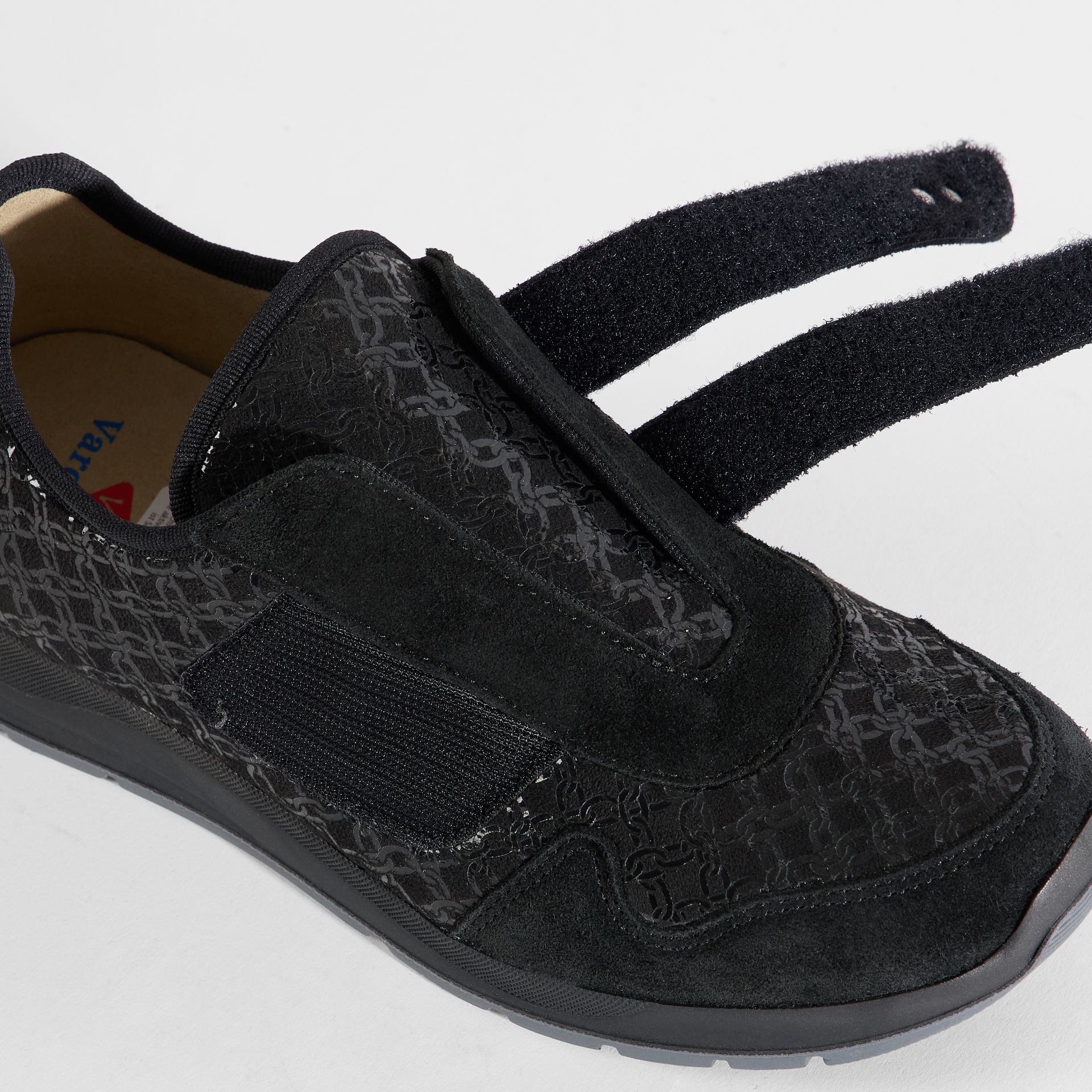 Schwarzer Damenschuh mit Klettverschluss und geprägtem Obermaterial. Nahaufnahme.
