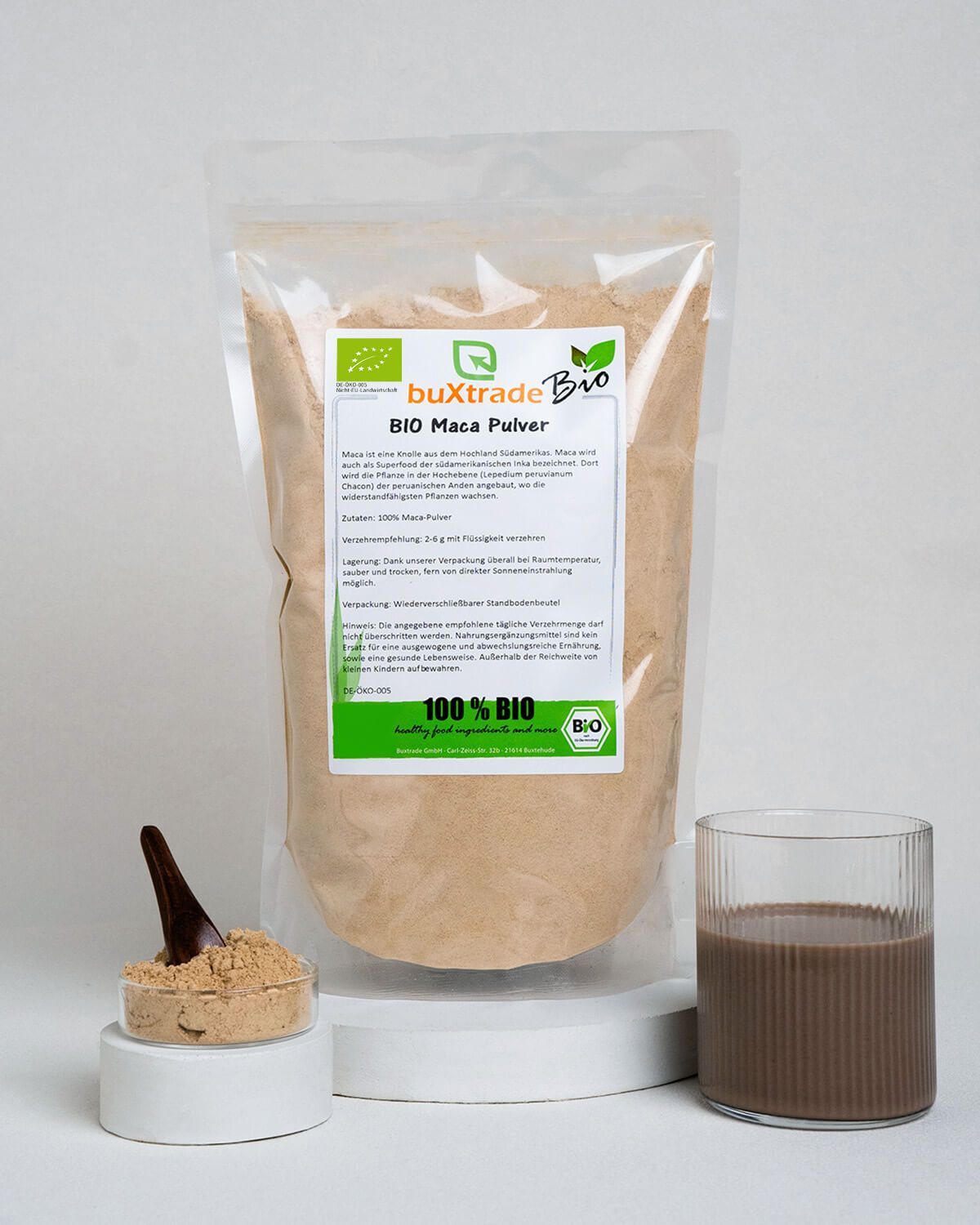 Bio Maca Pulver in einem Standbodenbeutel, daneben ein Glas mit Maca-Getränk und eine Schale mit Pulver.