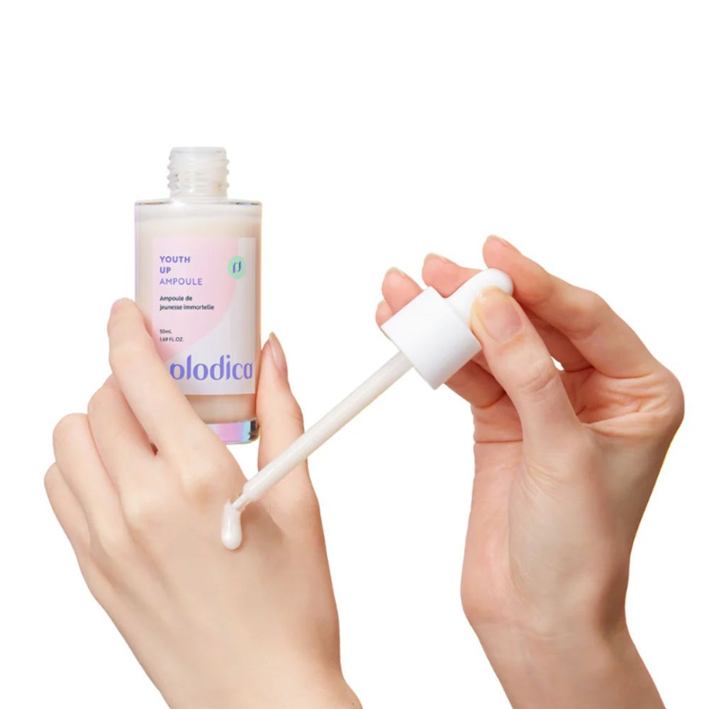 Hände halten Flasche und Pipette. Pipette tropft Flüssigkeit. Flasche mit rosa Etikett: Youth Up Ampoule, Plodica.