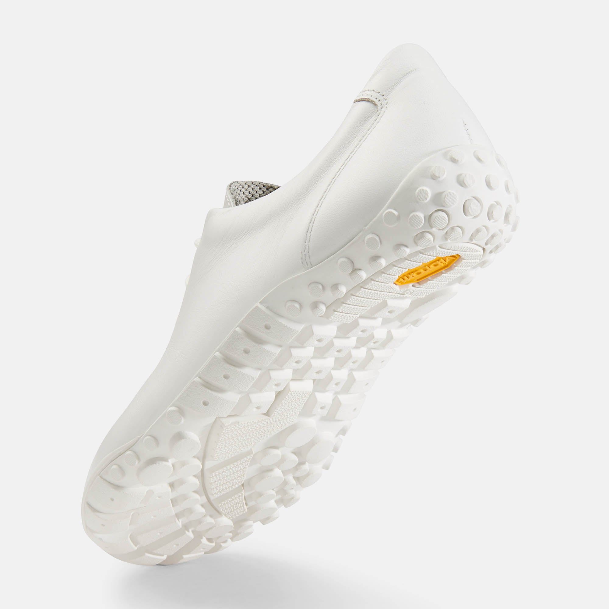 Weißer Schuh. Breite Passform. Hellgraues Innenfutter. Gelbe Sohle mit Noppen. Perspektivische Ansicht. Glattes Leder.