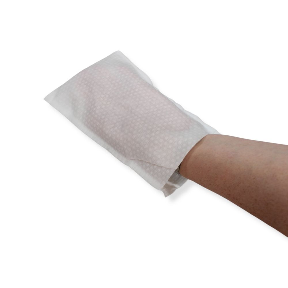 Einmalwaschhandschuh auf Arm. Weißes Material mit Wabenstruktur. Arm in der Öffnung des Handschuhs.