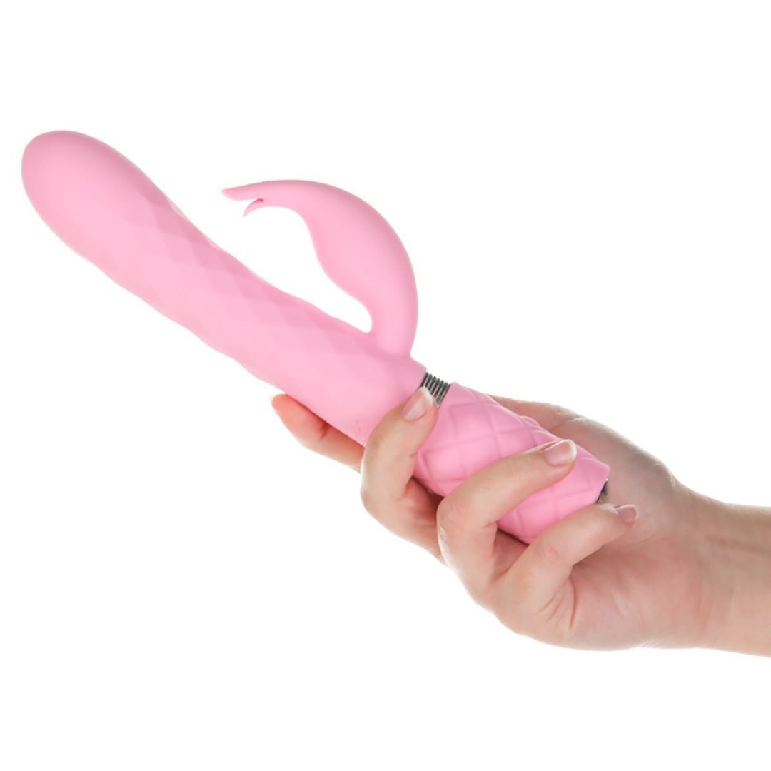 Rosa Vibrator in einer Hand gehalten. Geriffelte Oberfläche, Hasenohren-Design. Silberfarbener Ring am Schaft. Unterteil mit Rautenmuster.