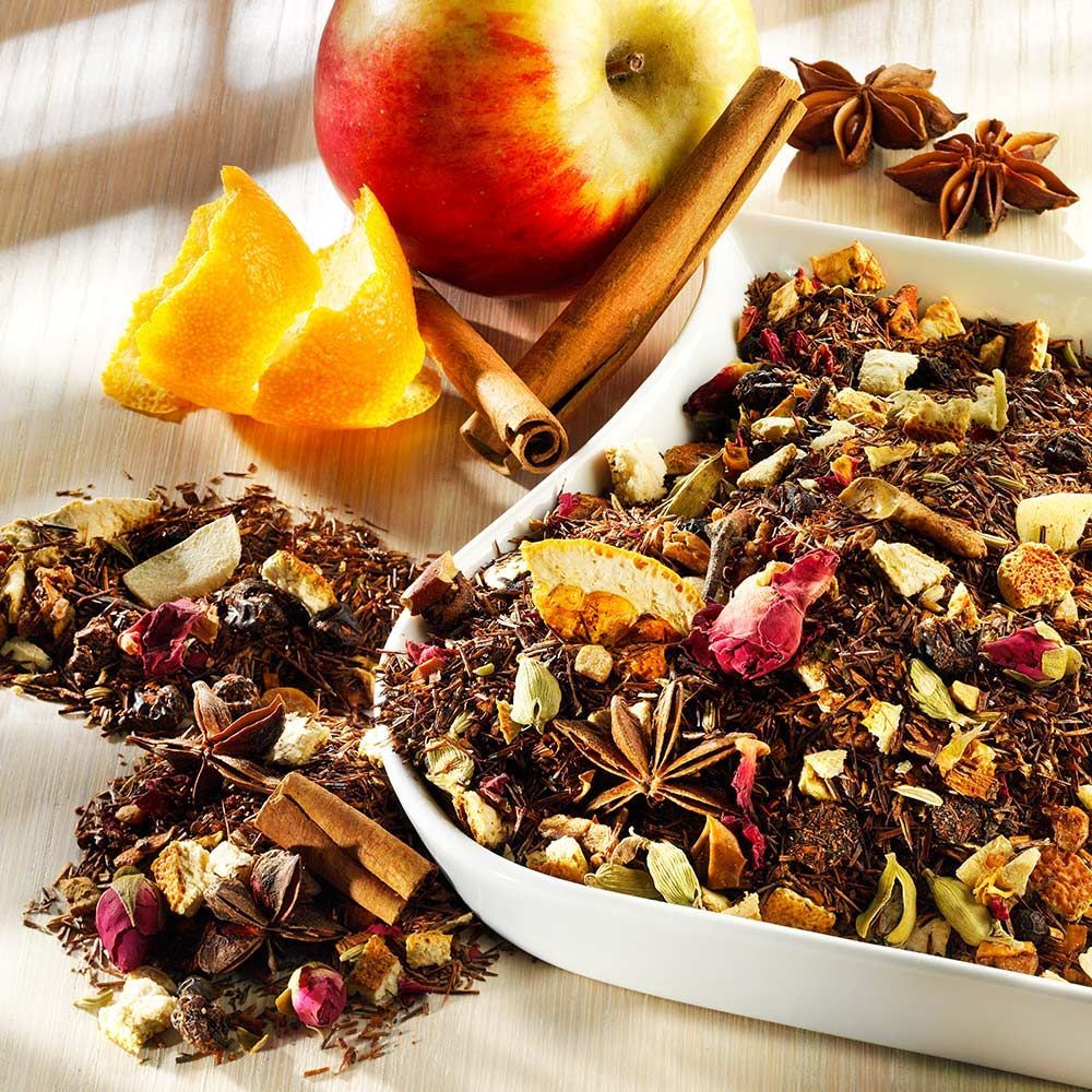 Schale mit Tee, Zimtstangen, Sternanis, Apfel und Orangenschale. Auf hellem Holzuntergrund.
