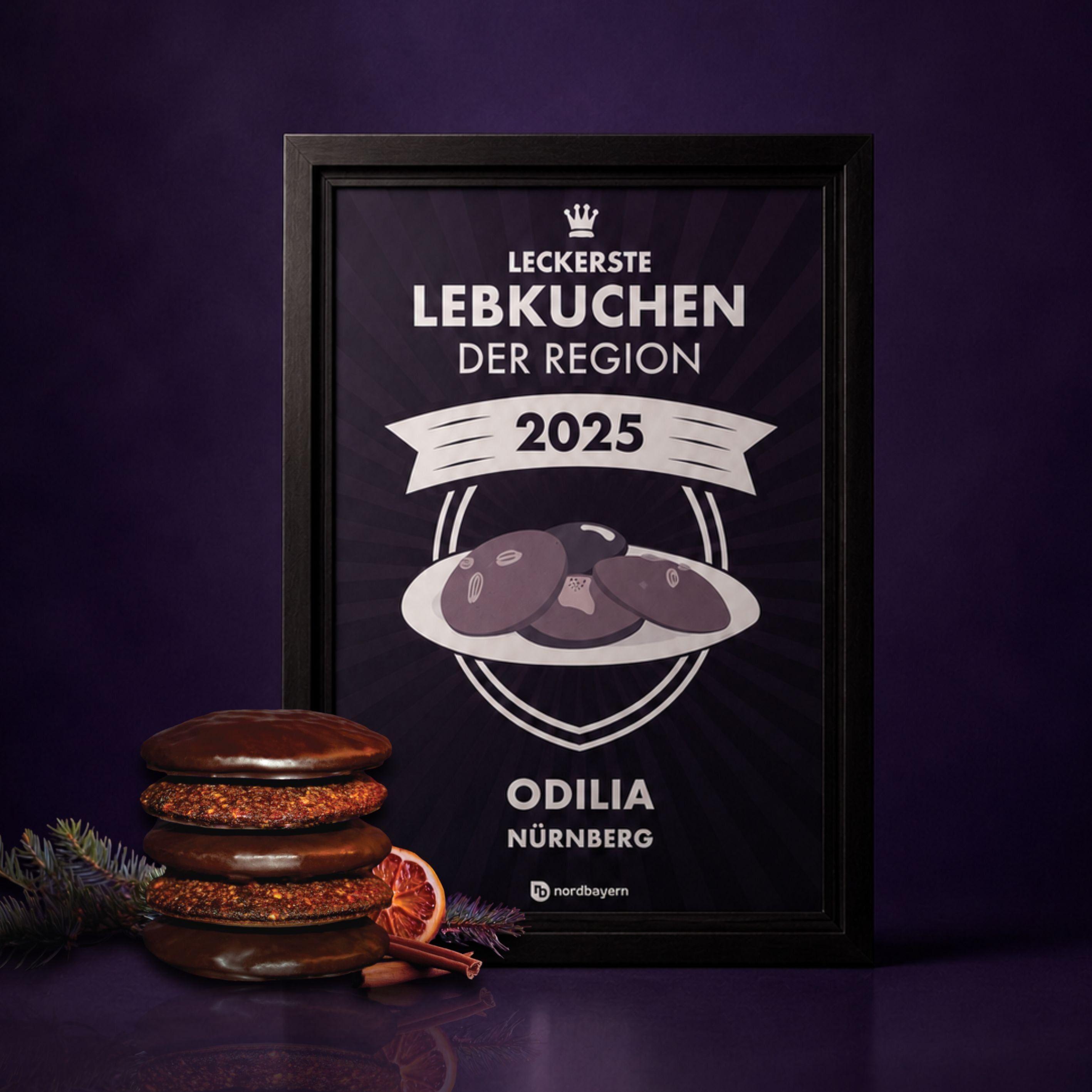 Gerahmter Preis für 'Leckerste Lebkuchen der Region 2025' von Odilia Nürnberg. Daneben gestapelte Lebkuchen.