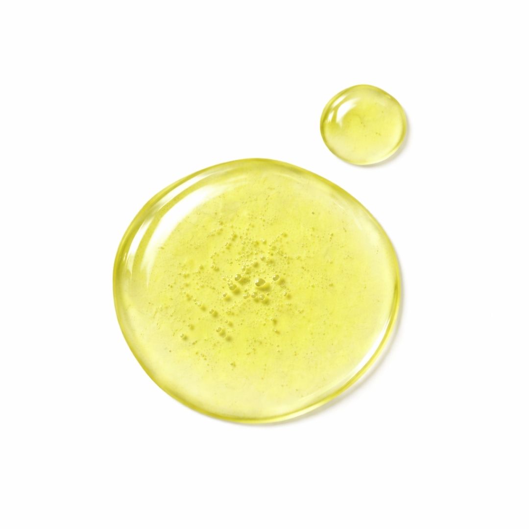 Zwei gelbe Flüssigkeitstropfen auf weißem Hintergrund. Der größere Tropfen ist rund, der kleinere daneben.