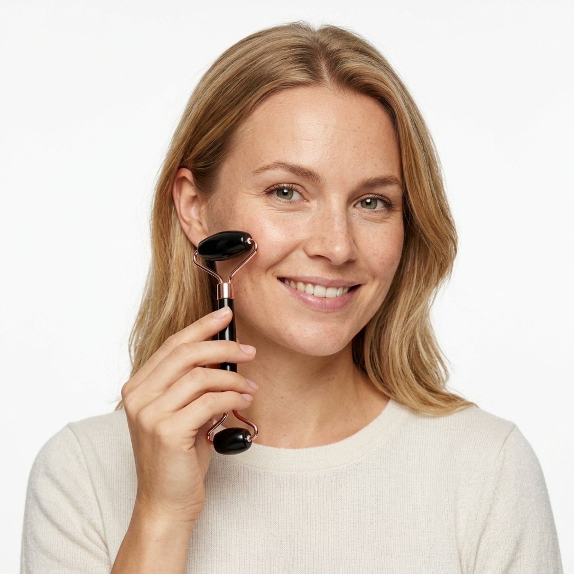 Frau mit einem schwarzen Jade-Roller im Gesicht, lächelnd.