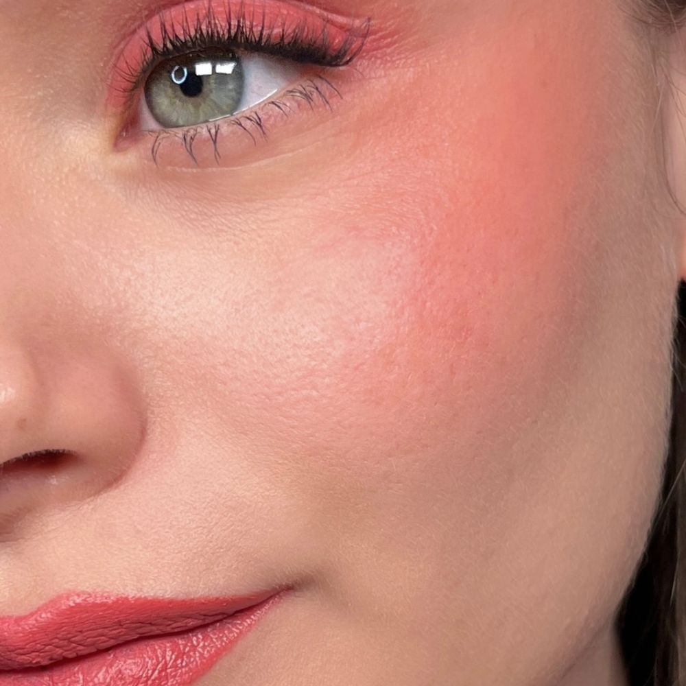 Nahaufnahme eines Auges mit rosa Lidschatten, Rouge und Lippenstift. Grüne Augen.