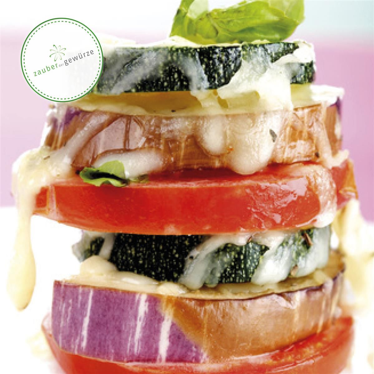 Geschichteter Auflauf aus Tomaten, Zucchini und Aubergine. Mit Käse überbacken und Basilikumblättern.