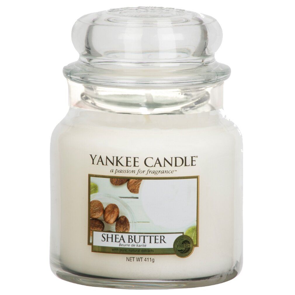 Yankee Candle Shea Butter Duftkerze. Glasbehälter mit Deckel. Etikett mit Produktname und Abbildung von Sheanüssen. Nettogewicht 411g.