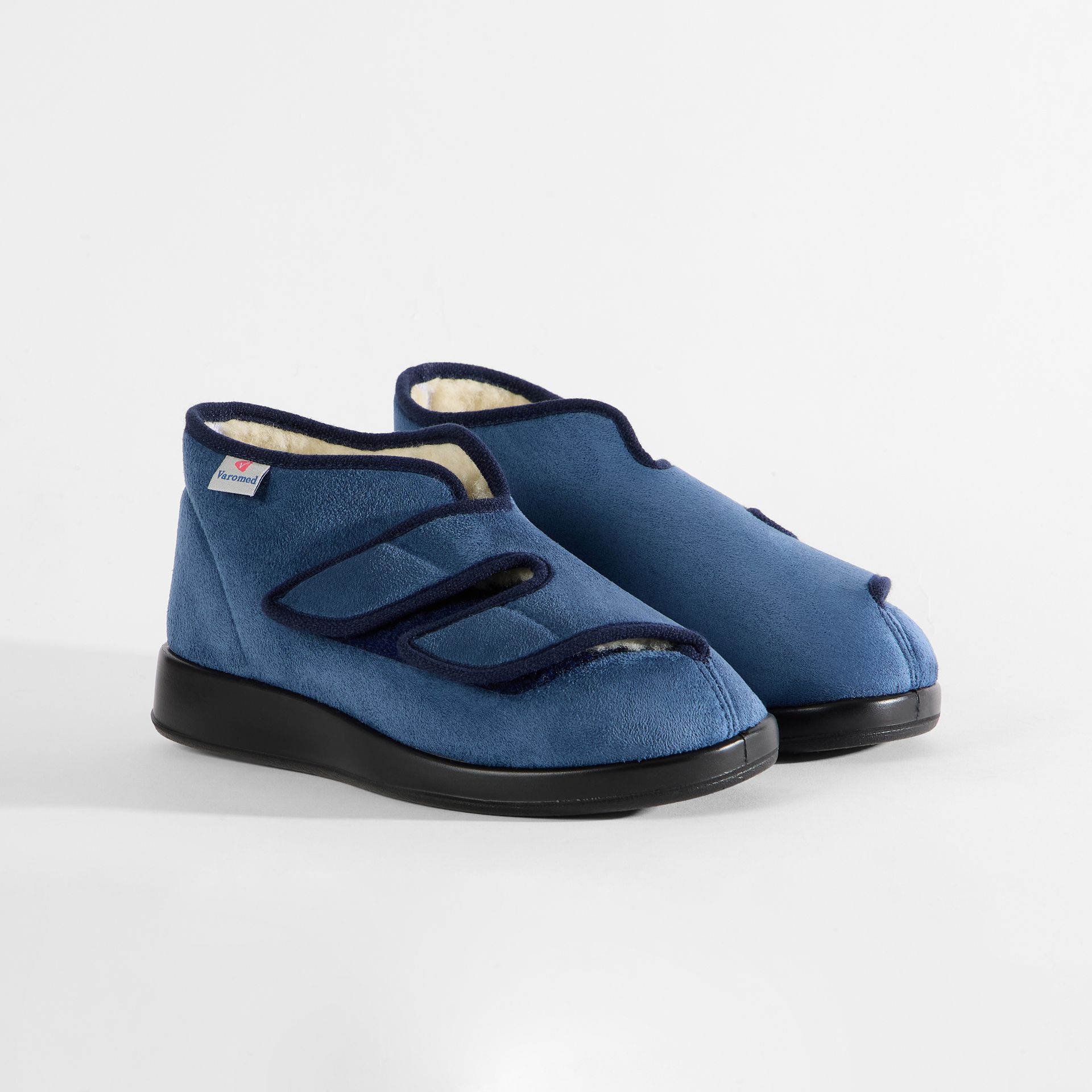 Blaue Hausschuhe mit Klettverschluss, weichem Futter und Gummisohle.