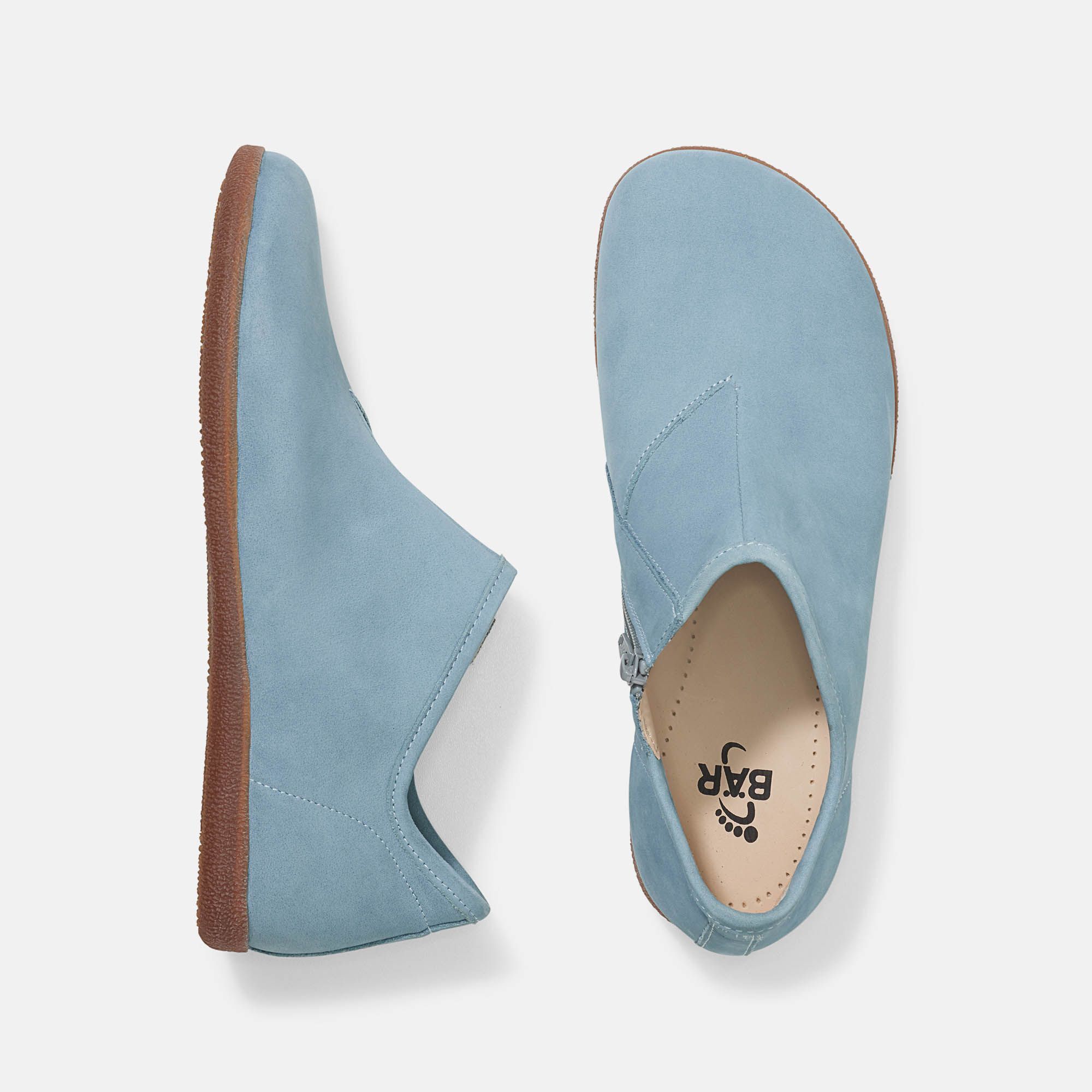 Hellblaue Slipper, Ansicht von oben. Braune Sohle, Reißverschluss, Logo. Weite Form.