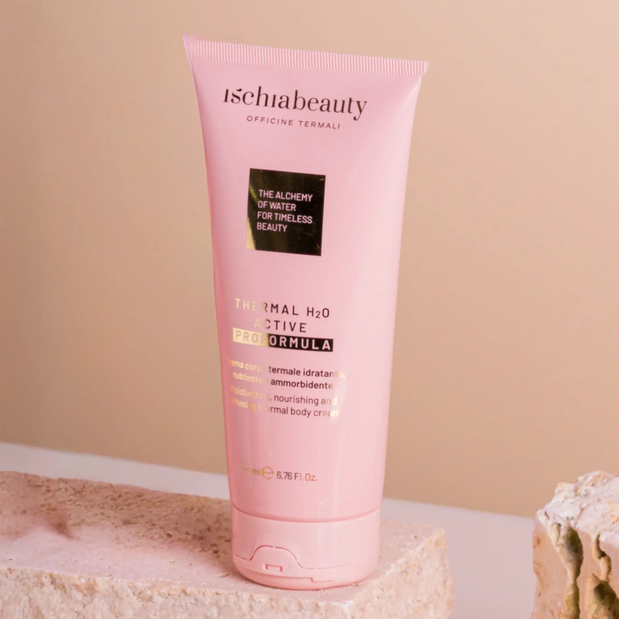 Rosa Tube mit Produkttext. Aufschrift: ischiabeauty, Thermal H2O Active Pro Formula. Auf Stein platziert.