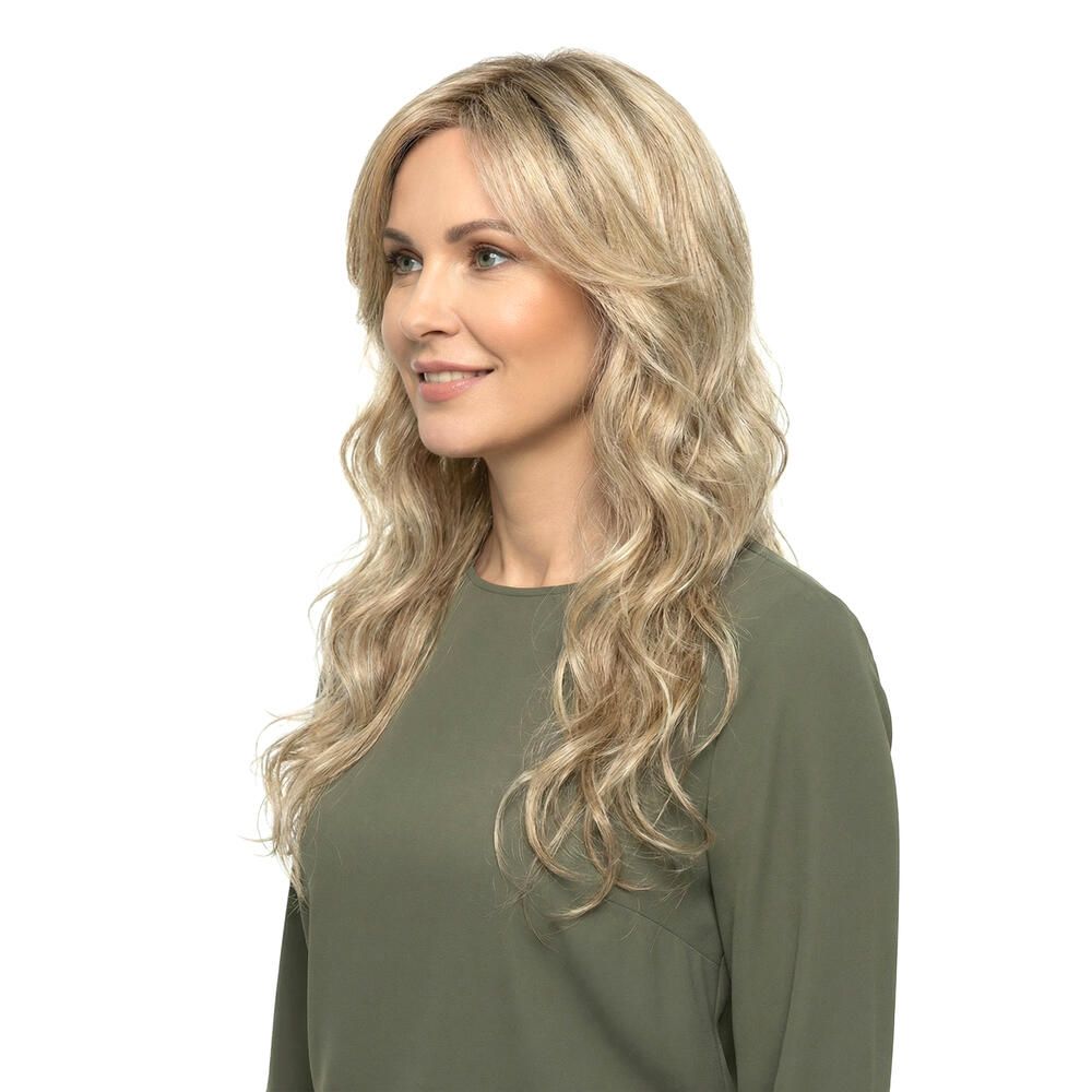 Blond gewellte Perücke mit Pony, im Profil. Die Frau trägt ein grünes Oberteil. Hintergrund weiß.