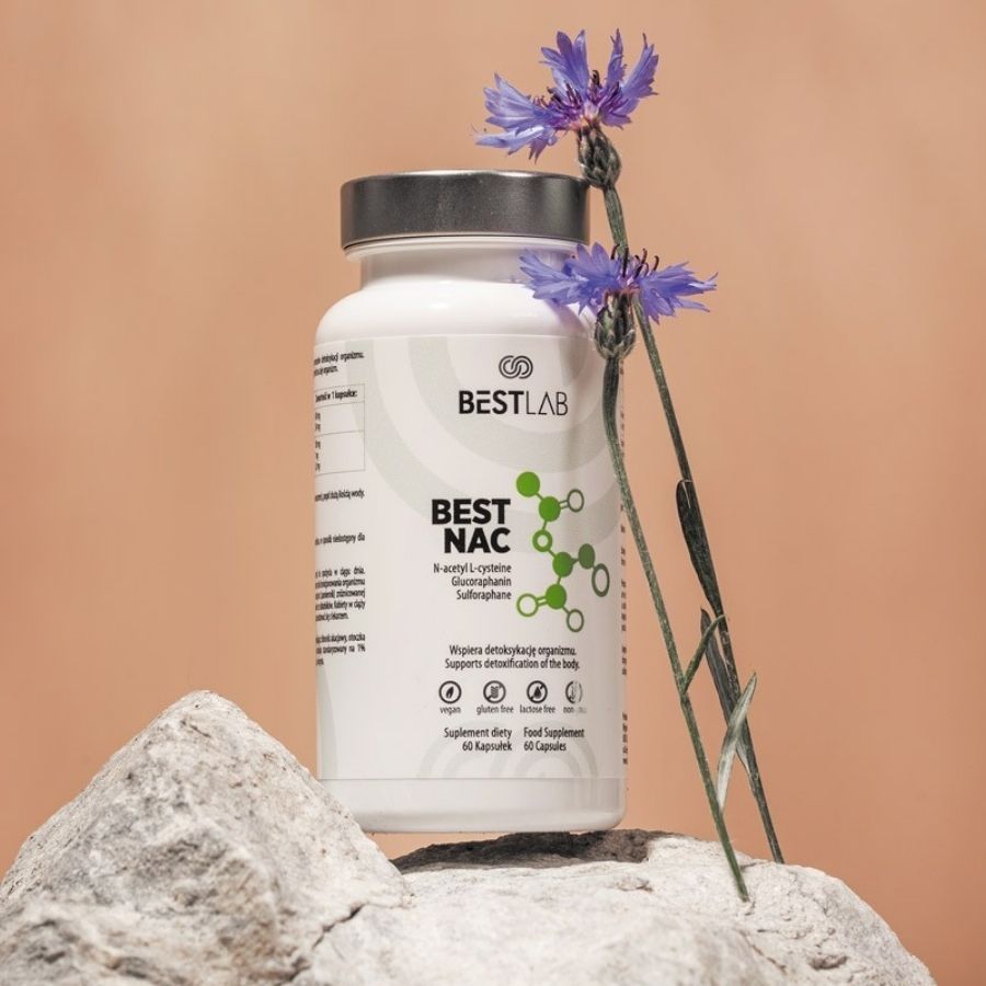 Weiße Flasche BEST LAB NAC auf Stein. Hintergrund: beige. Dekoration: blaue Blüten.