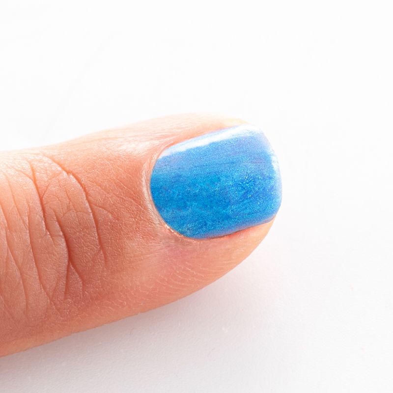 Blau lackierter Fingernagel. Der Nagellack ist glänzend und hat eine helle, blaue Farbe.