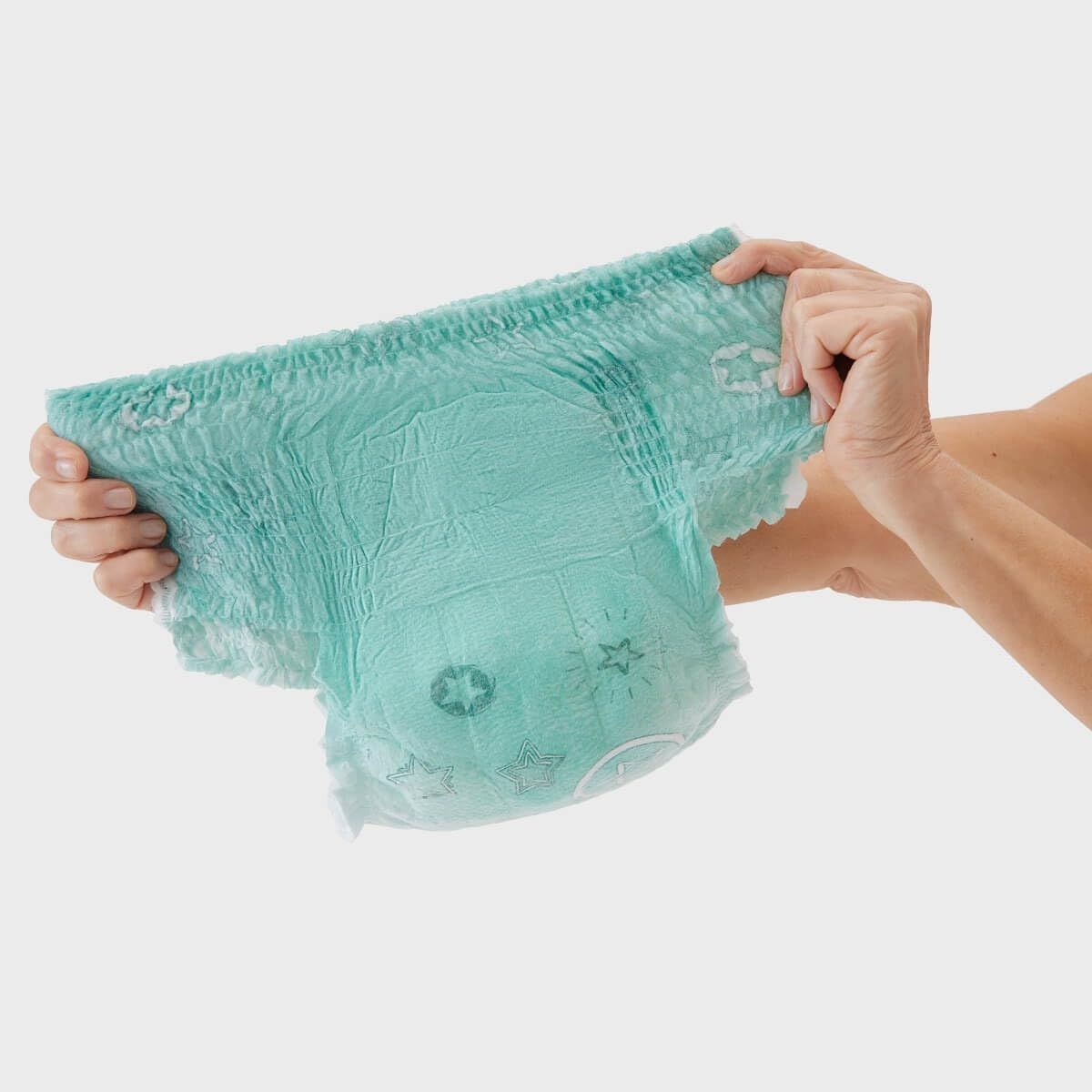Hellgrüne Pyjamahose, von Händen gehalten und gedehnt. Sterne und Kreise auf der Oberfläche. Elastische Bündchen.