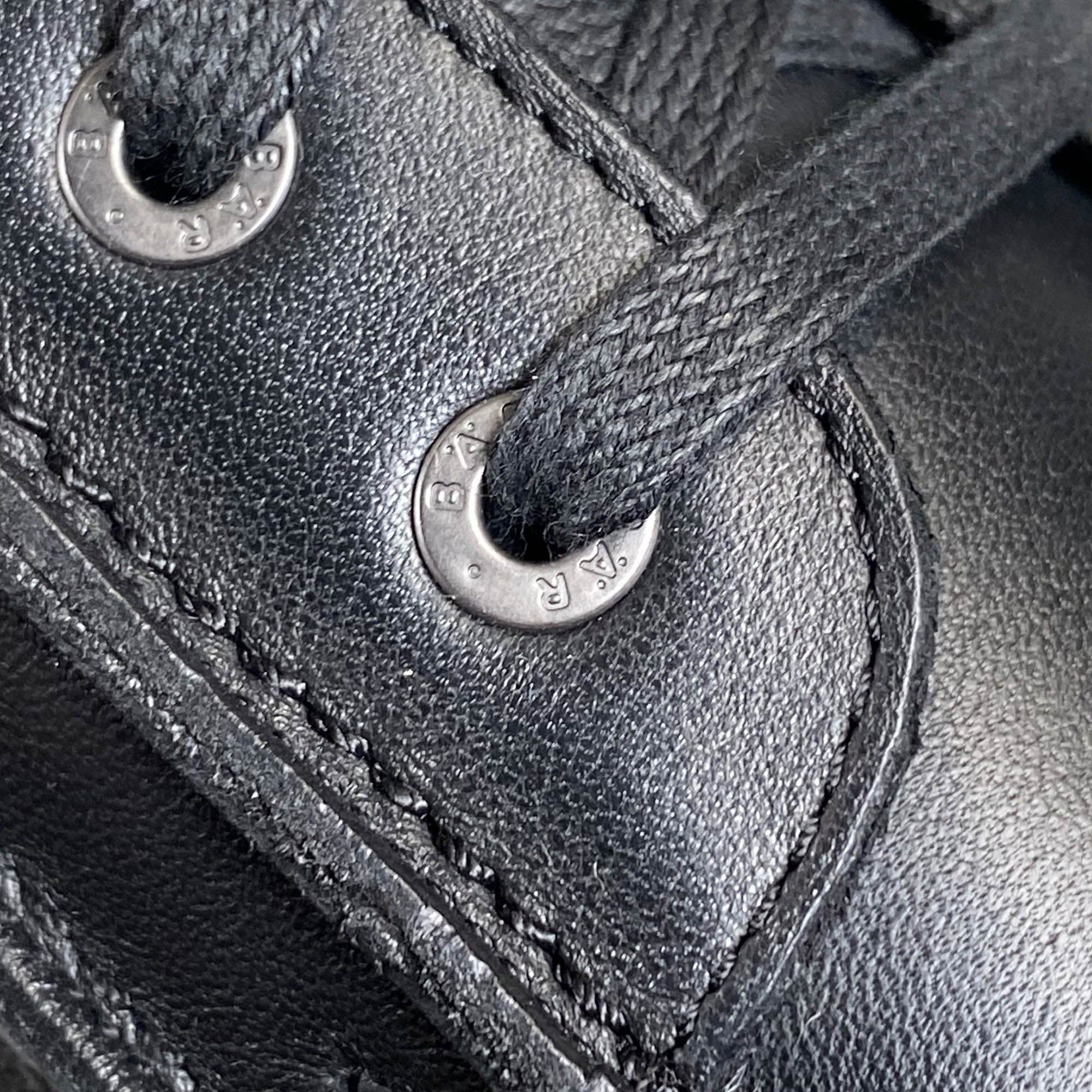 Nahaufnahme von zwei Ösen an einer schwarzen Stiefelette. Metallösen mit Prägung.