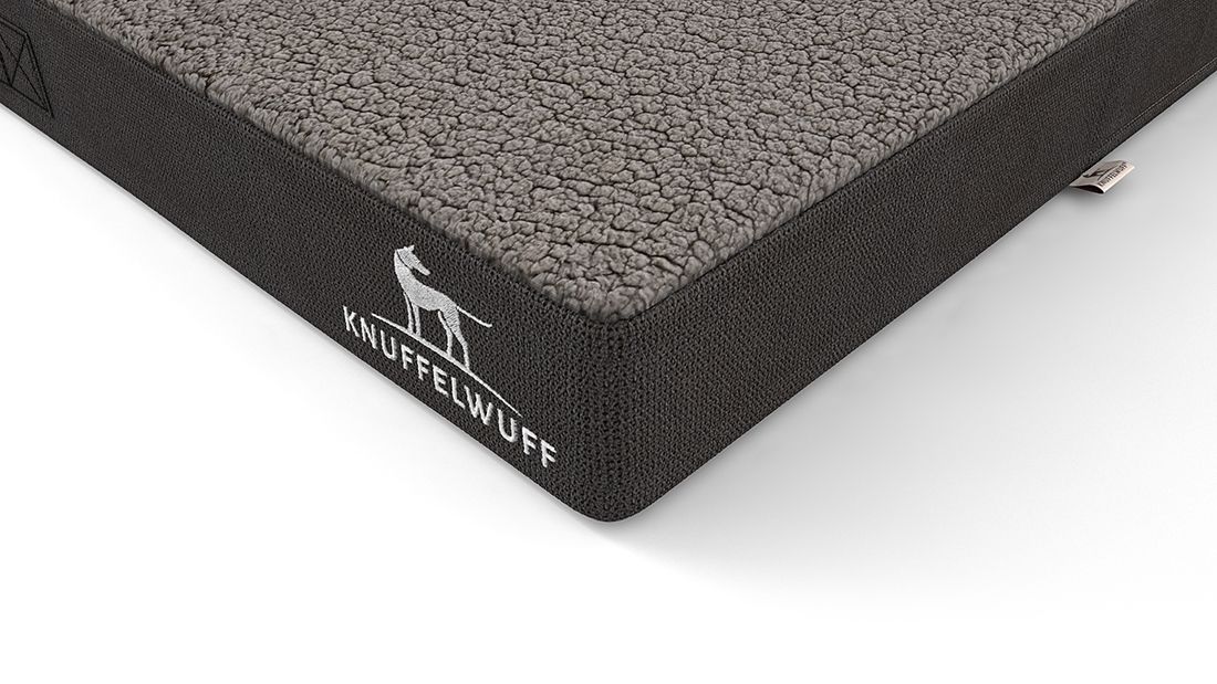Ecke der orthopädischen Hundematte Ellenie. Graue Oberfläche, schwarzer Rand. Knuffelwuff Logo.