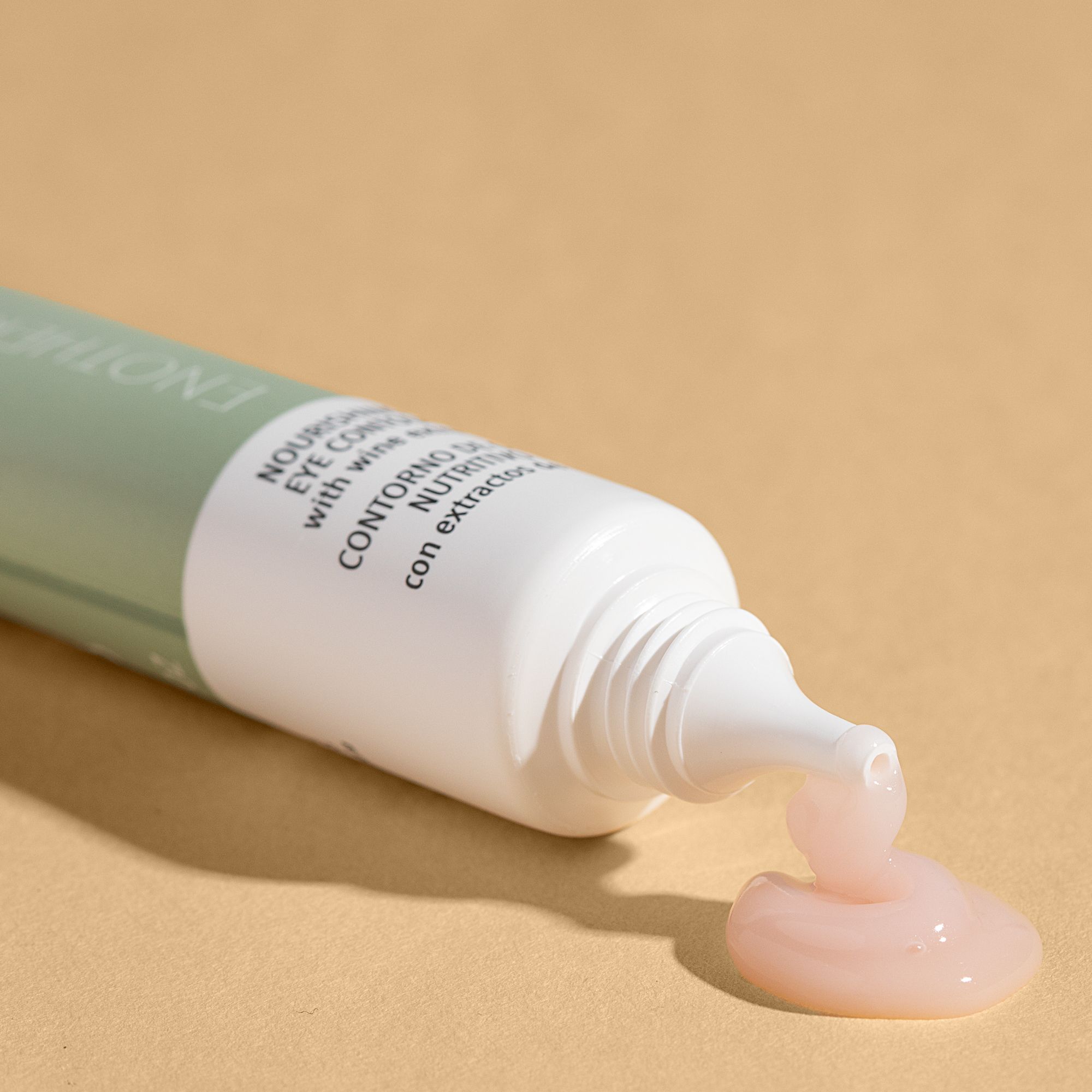 Geöffnete Tube, Creme tritt aus. Text: Nährende Augencontour-Creme. Hintergrund: Beige.