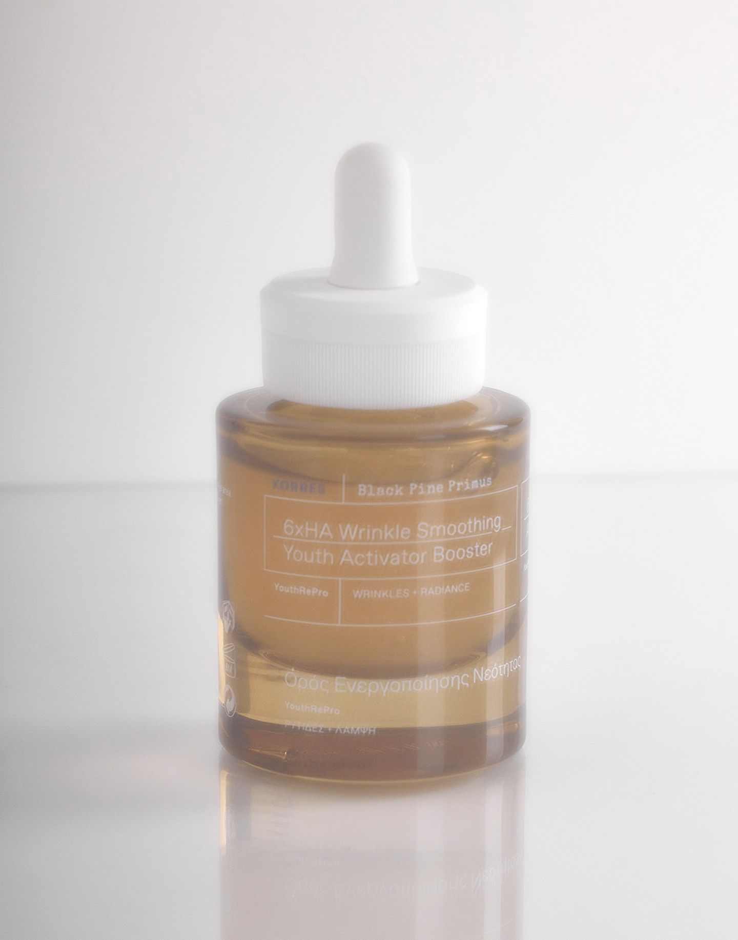 Braune Glasflasche mit weißem Tropfer. Aufschrift: Black Pine Primus, 6xHA Wrinkle Smoothing Youth Activator Booster, KORRES.